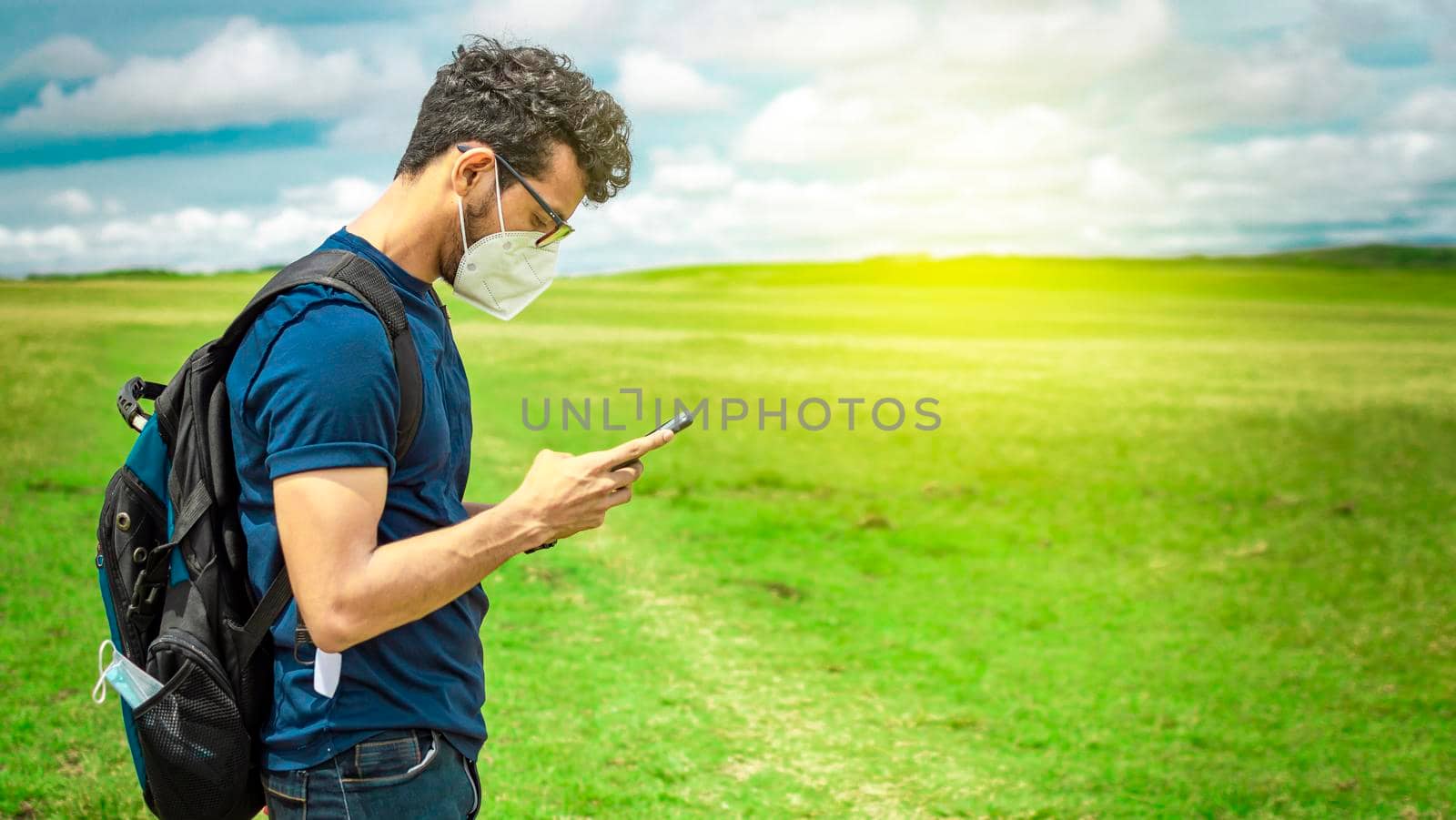 Adventurous man in the field with phone, man with backpack in the field chatting