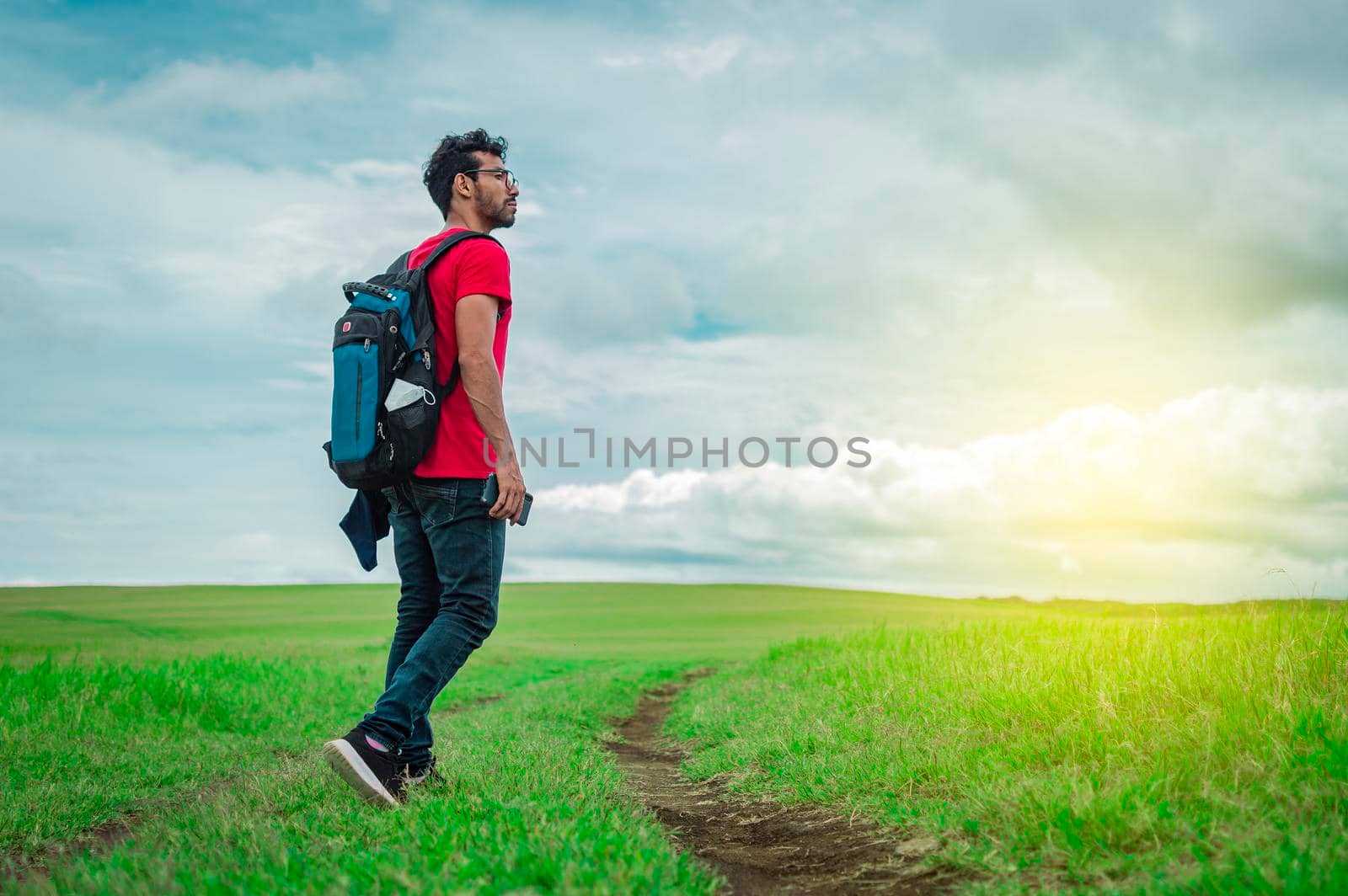 Adventurous man in the field, man with backpack in the field looking