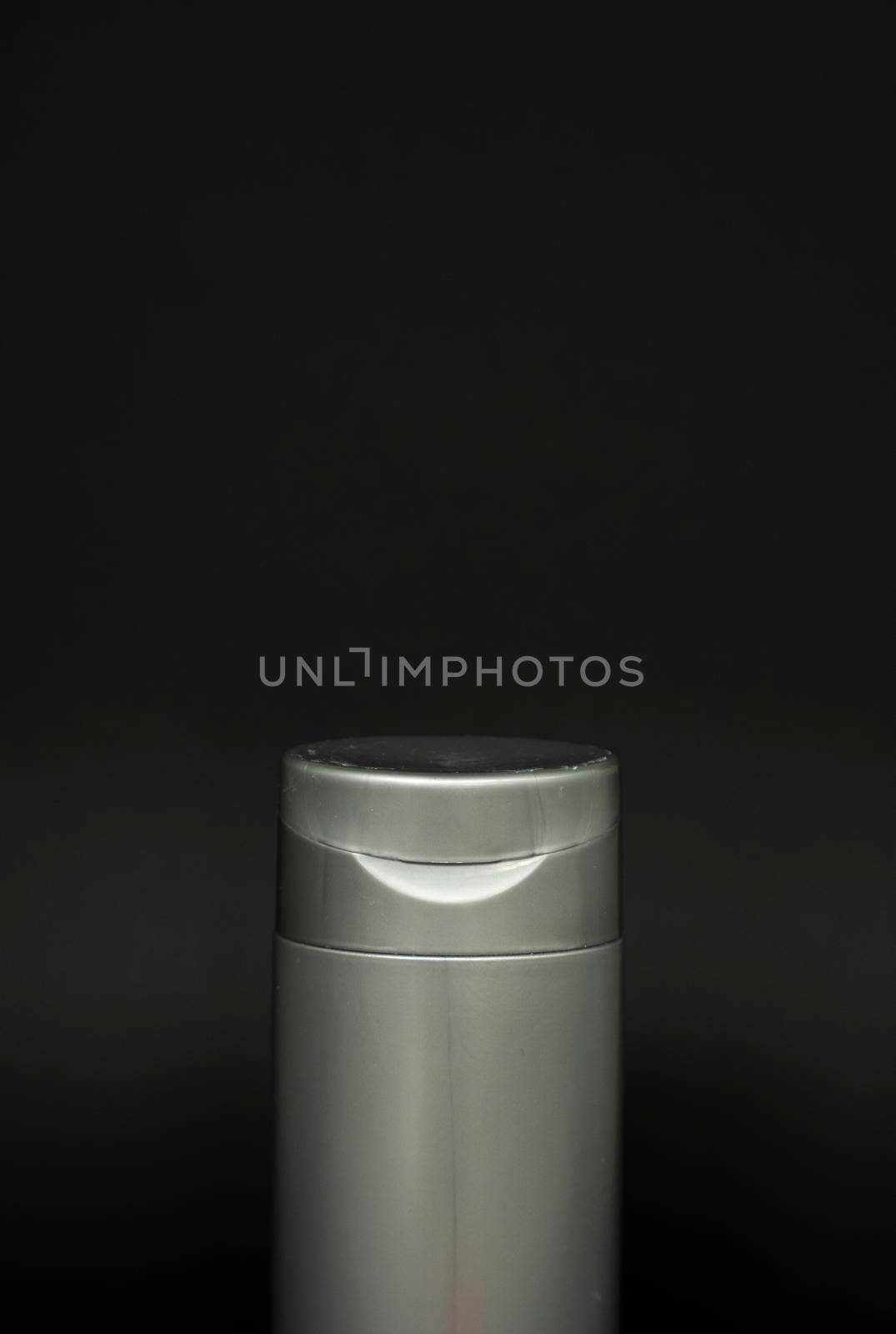 Black shampoo packaging mockup. Vertical empty plastic cosmetic package for man, isolated on black background. Container of conditioner, hair rinse