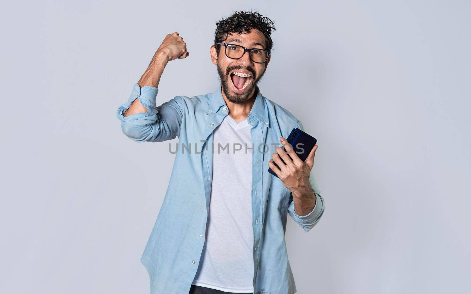 Happy man holding a smartphone and celebrating, Excited guy looking at his smartphone