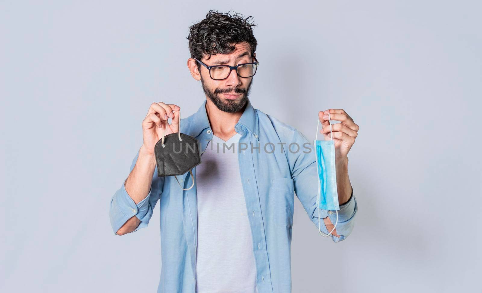 Man deciding to wear surgical mask, Latin man deciding to wear surgical mask on isolated background by isaiphoto