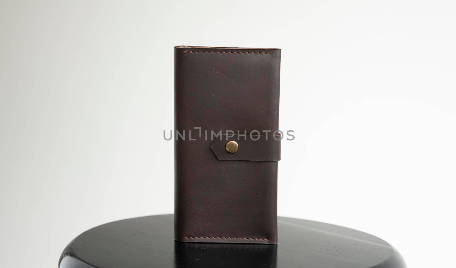 Man's handmade genuine leather wallet for banknotes and credit cards on a black surface with white background. Style, retro, fashion, vintage and elegance