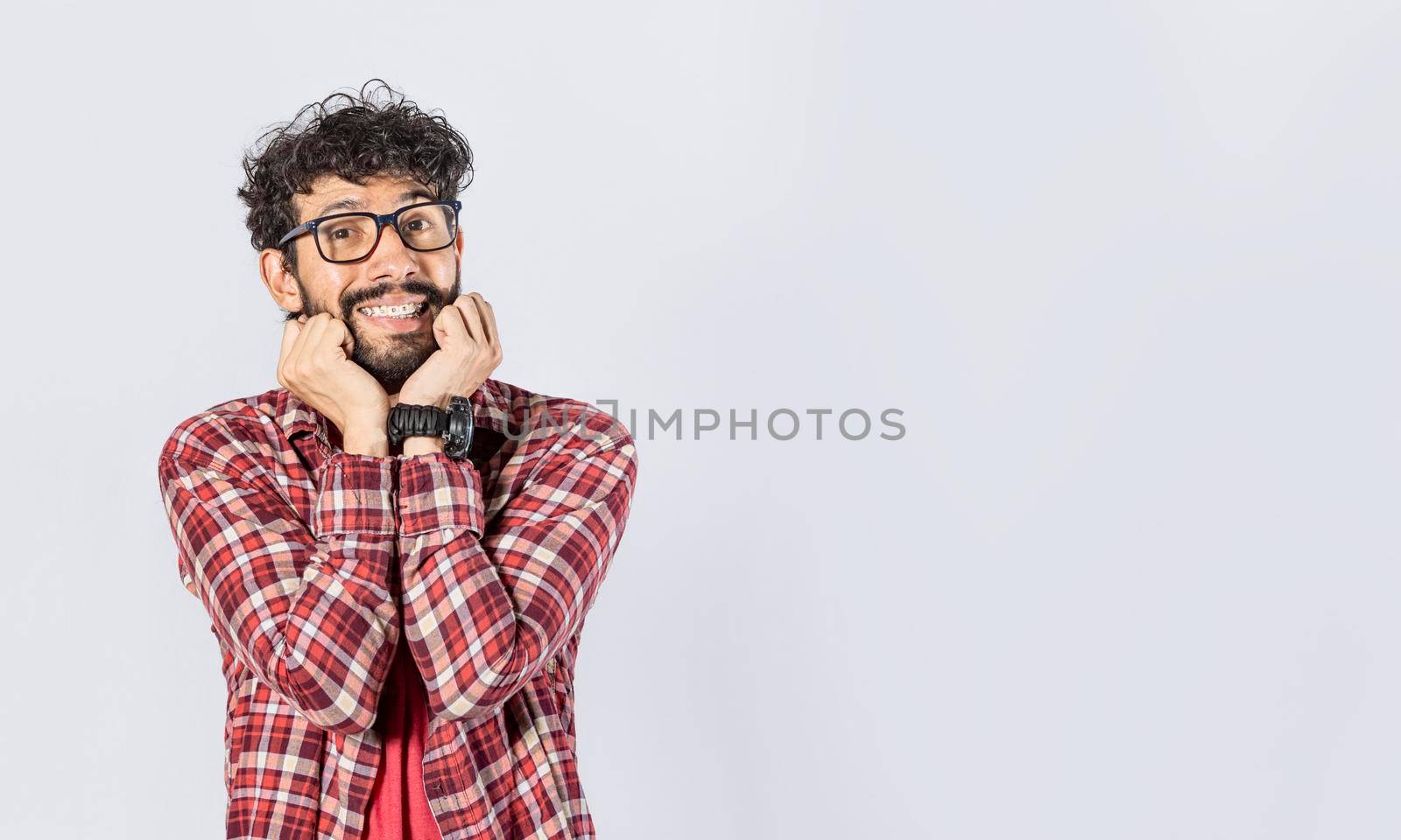 Guy with glasses smiling friendly, Close up of a man smiling on isolated background, face of a guy smiling with hands on his cheek by isaiphoto
