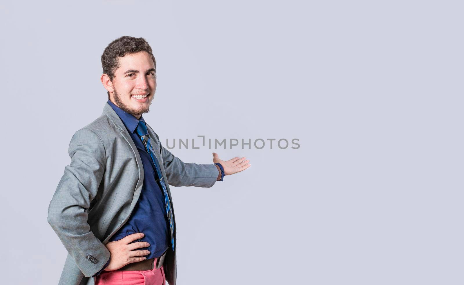 Man pointing back and presenting a product, man in a suit welcoming, man looking at the camera presenting a product, person inviting
