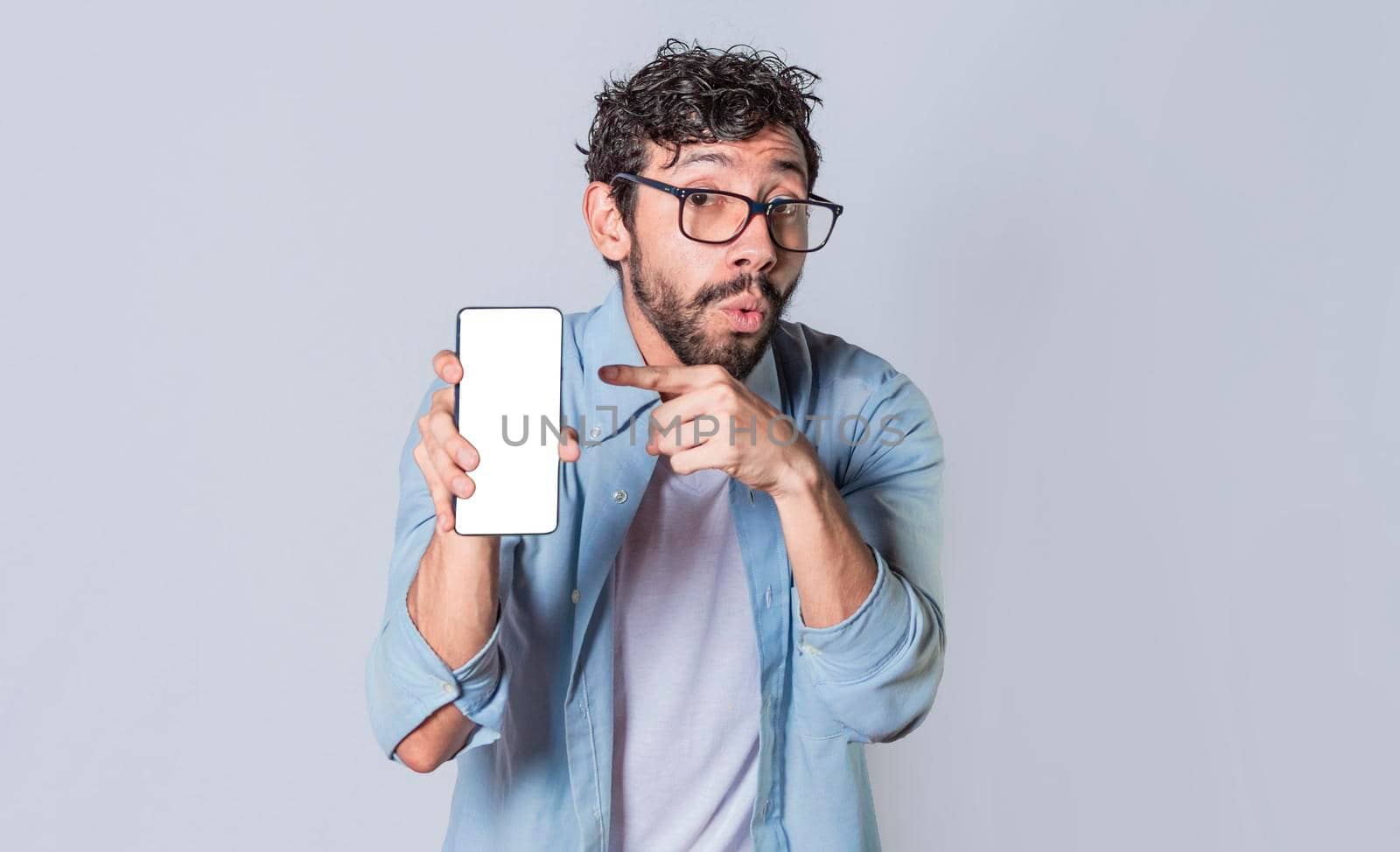 Young man showing blank cell phone screen, guy showing and pointing at his cell phone screen by isaiphoto
