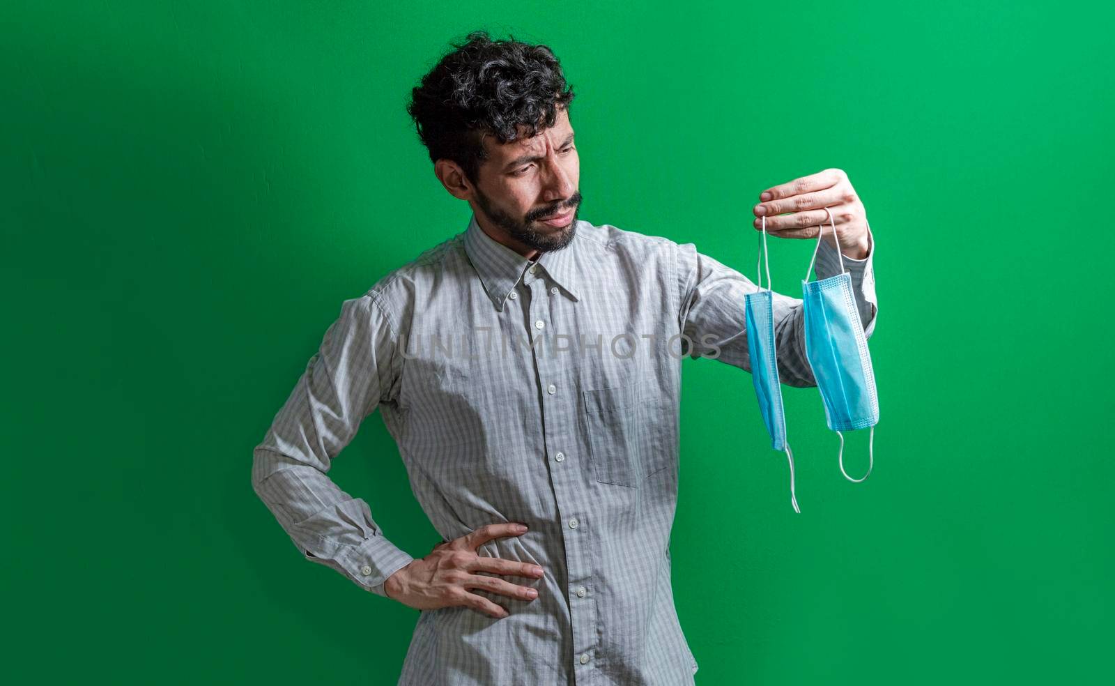 Man deciding to wear surgical mask, Latin man deciding to wear surgical mask on isolated background
