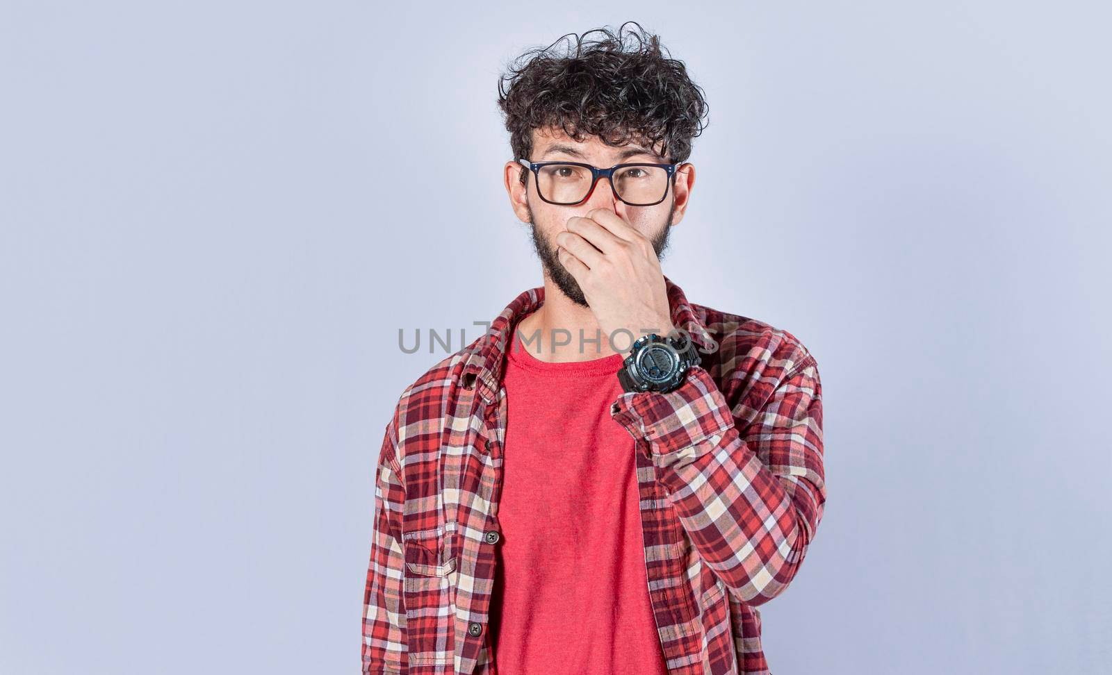 Close up of a man covering his nose, a guy with a face of unpleasant odors, Latino man covering his nose by isaiphoto