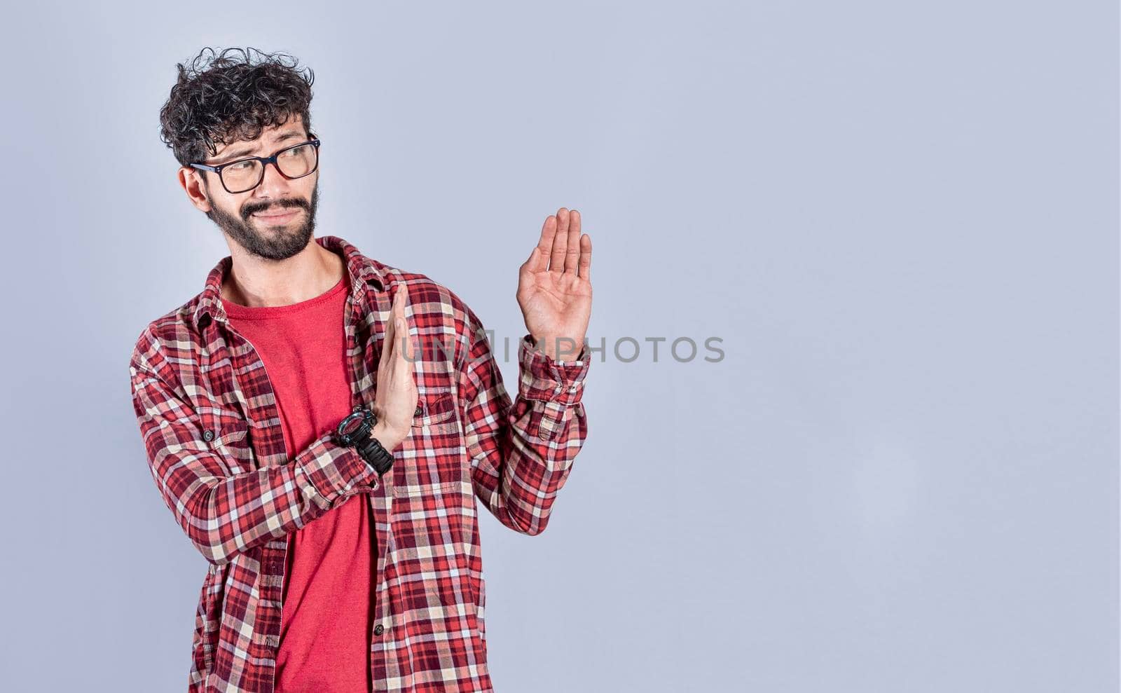 Disgusted intense man with rejection gesture, pulls palms in rejection, frowns in disgust