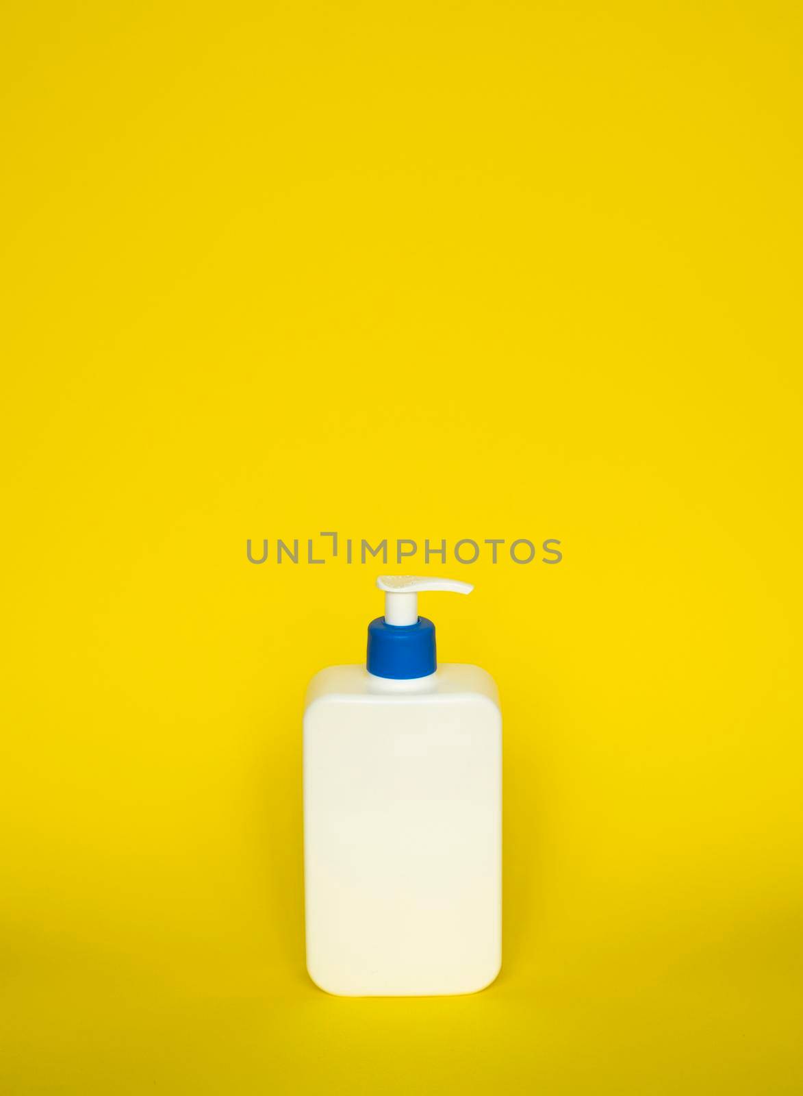 Liquid container for gel, lotion, cream, shampoo, bath foam. Cosmetic plastic bottle with blue dispenser pump on yellow background. Cosmetic packaging mockup with copy space. by vovsht