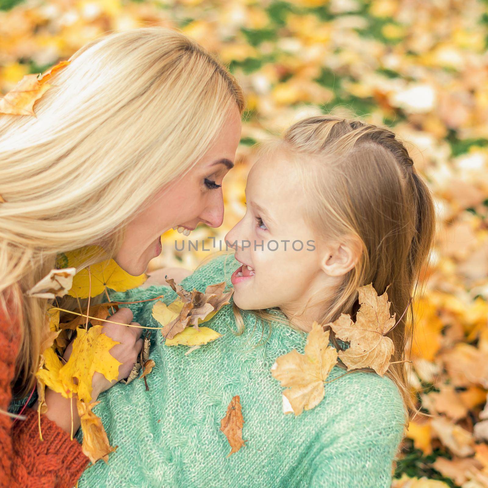 Beautiful young caucasian mother playing with her little child in the autumn park