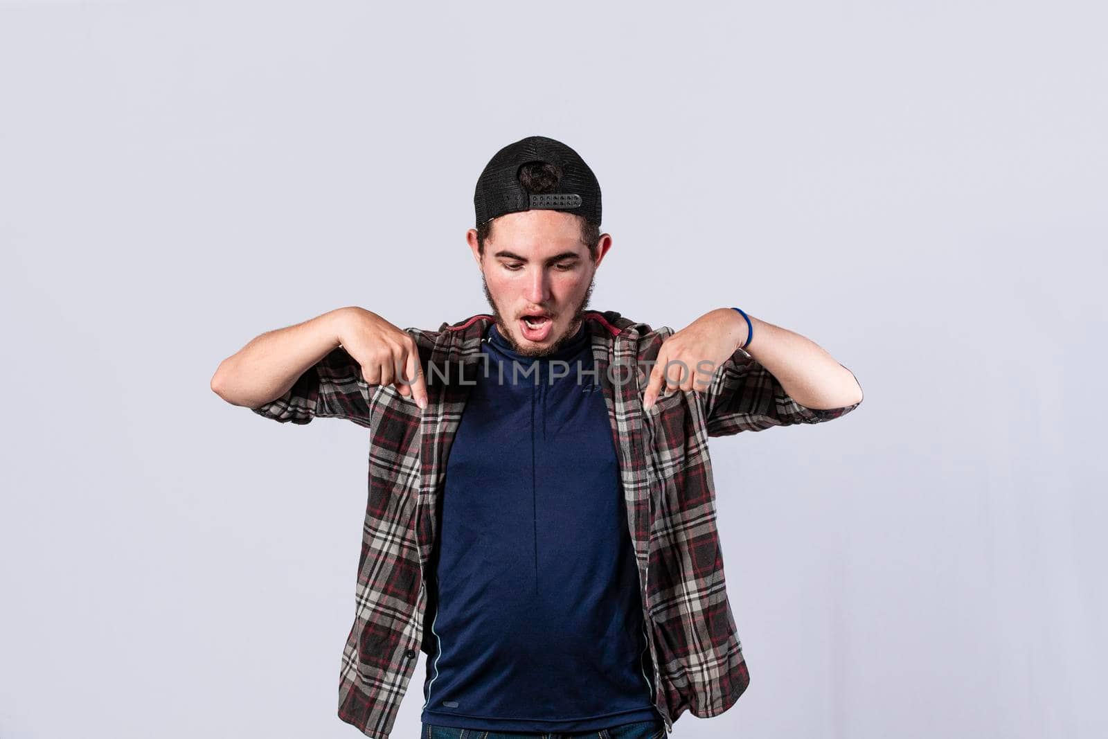 A man pointing down, surprised guy pointing his fingers down, amazed young man pointing down