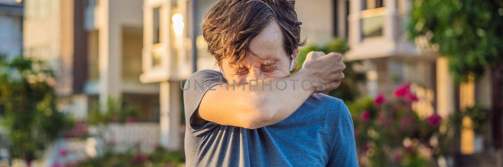 How to sneeze correctly. Man sneezes on the elbow. Concept of the spread of the virus. BANNER, LONG FORMAT