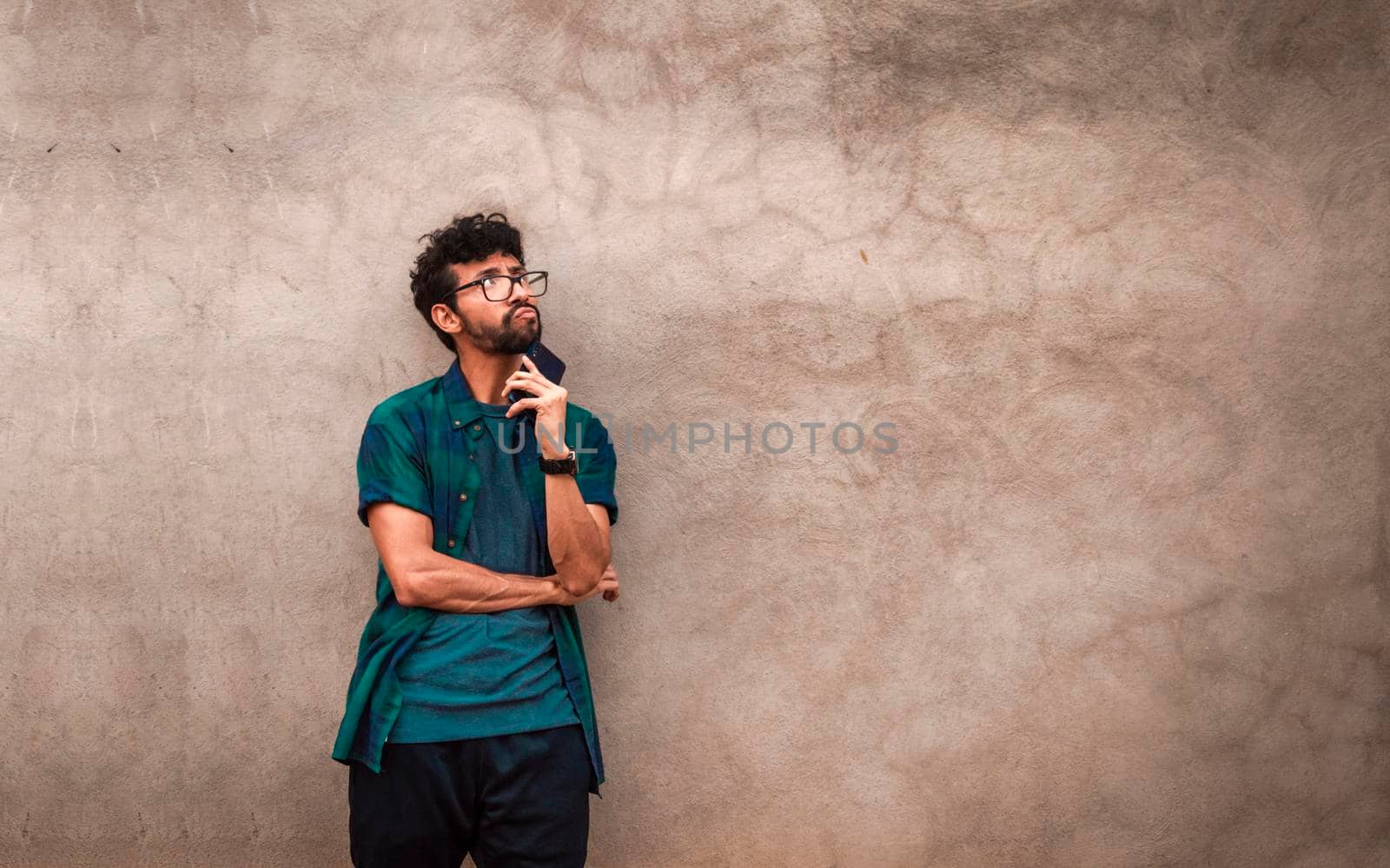 Pensive young latin man with hands in his pocket, pensive young man looking up