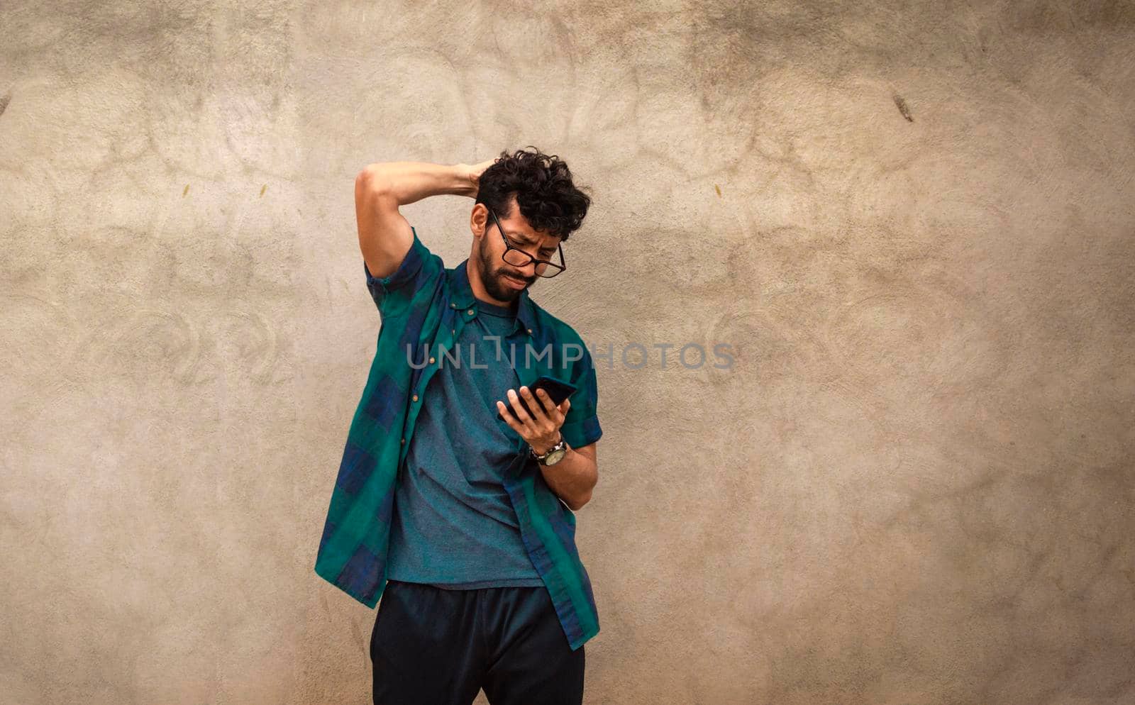 Confused man while looking at his cell phone, Confused guy while checking his cell phone