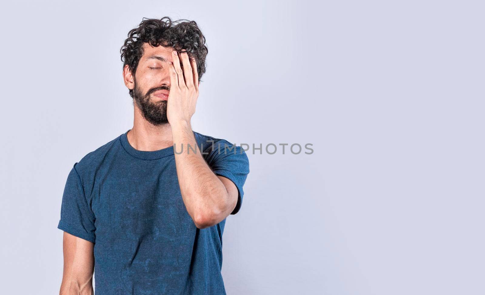 Tired and distressed man covering his face with his palm, Concept of a bored and tired man