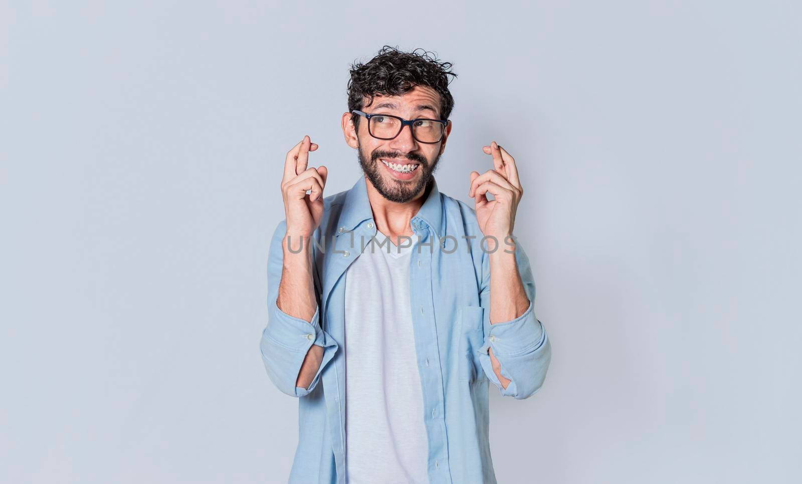 Happy man making a wish, latin guy crossing his fingers making a wish