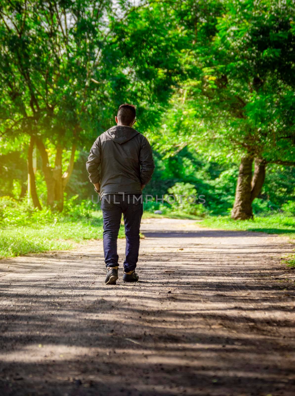 Man walking down a desolate road, man walking backwards on a road surrounded by vegetation