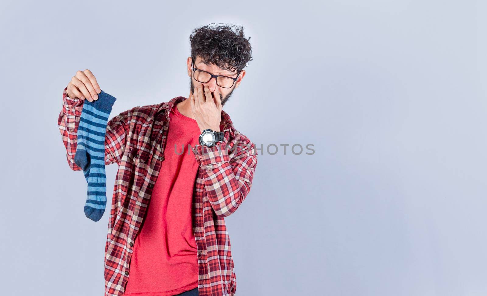 A man with a sock in his hand covering his nose, a guy with a stinky sock in his hand, smelly socks concept
