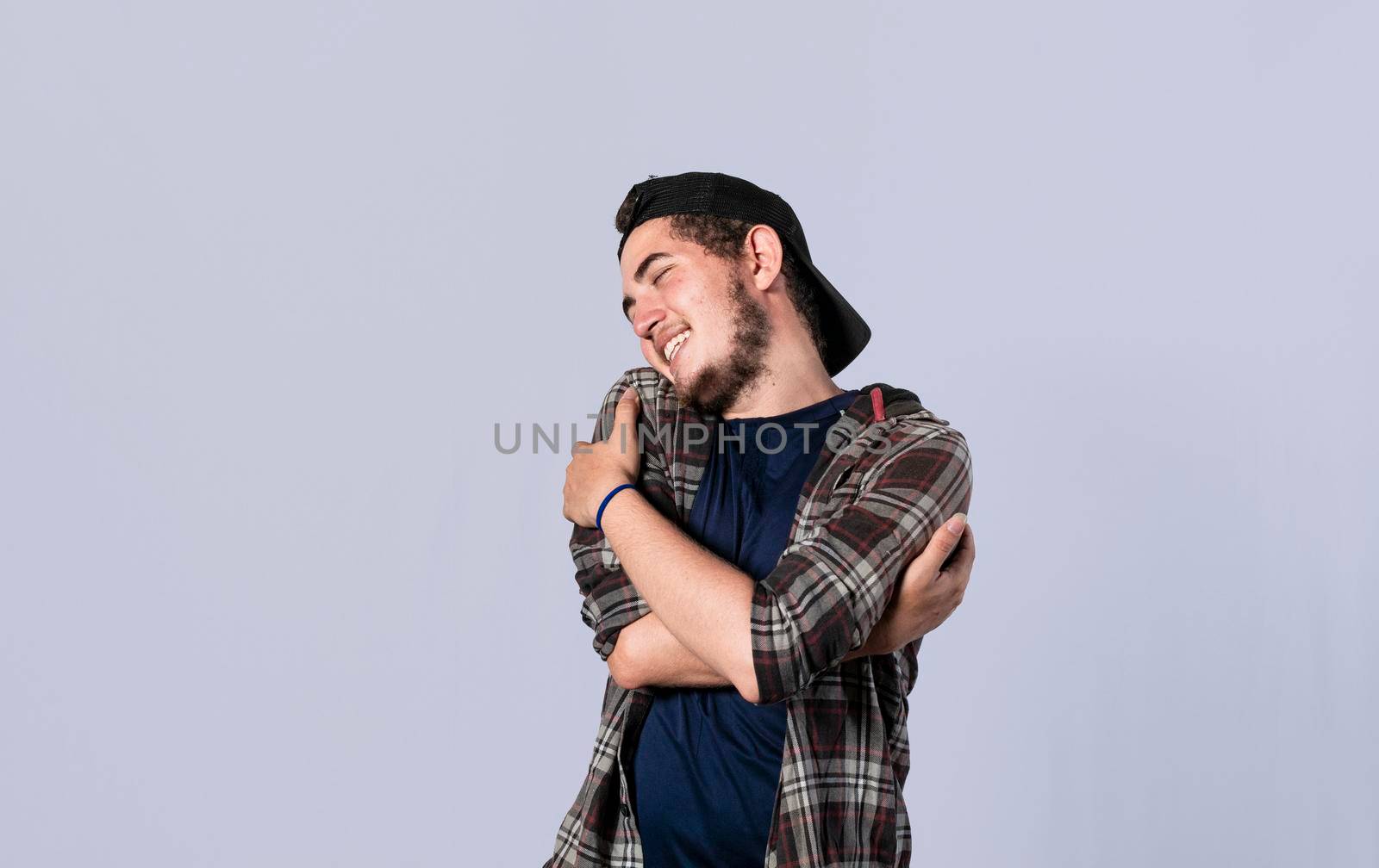 Friendly man hugging himself, Pleased young man hugging himself, Attractive positive looking friendly young man with a sincere smile embracing himself gratefully