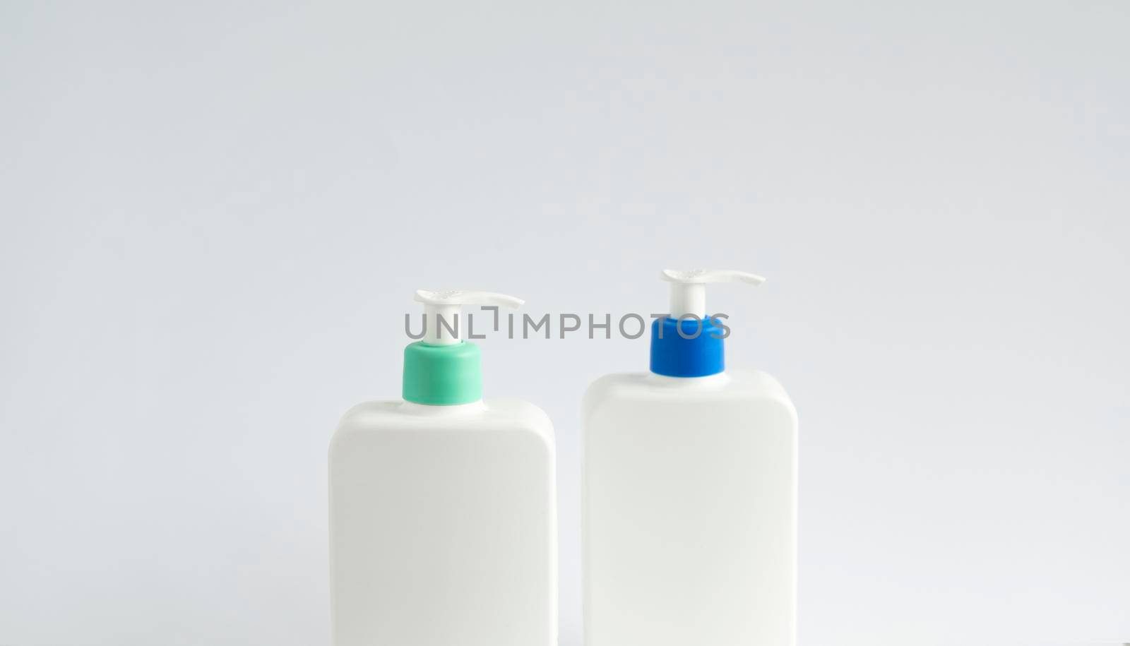 Two white unbranded dispenser bottles on white background. Cosmetic packaging mockup with copy space. by vovsht