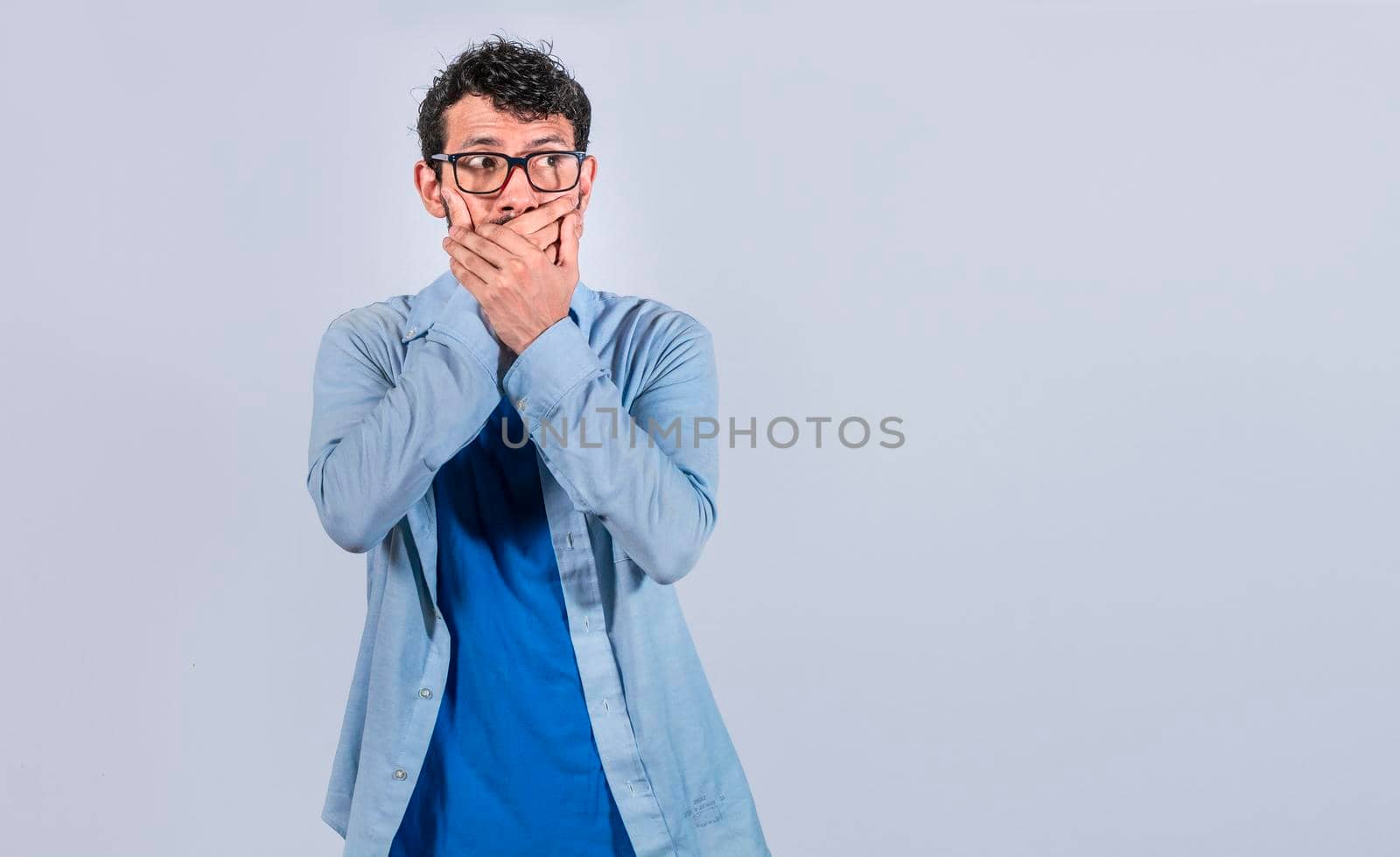 Surprised man covering his mouth looking to the side, Surprised man in glasses covering his mouth looking to the side, concept of man keeping a secret by isaiphoto