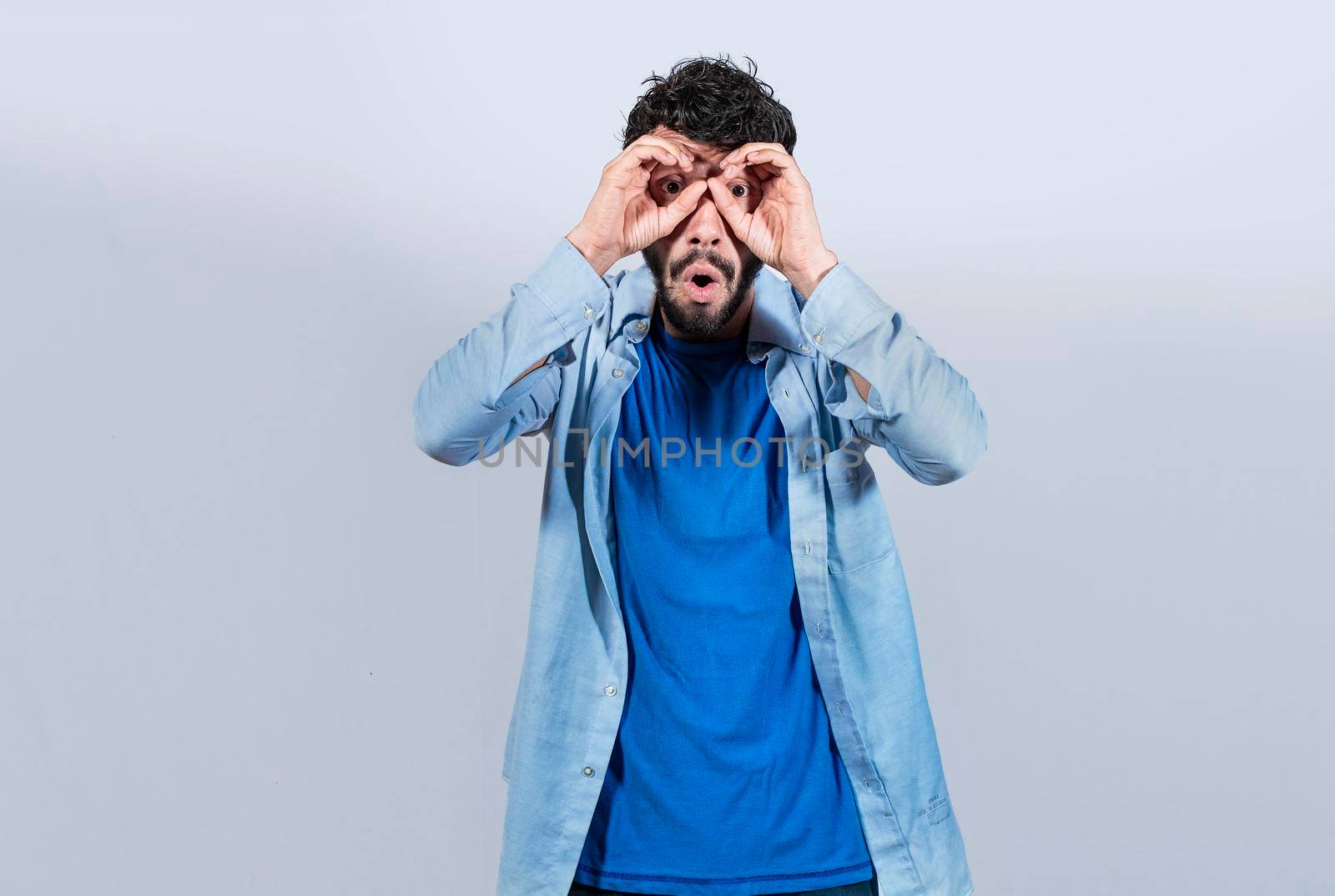 Curious man making binoculars gesture, Guy on isolated background making binoculars gesture, Man making binoculars gesture, man using his fists as binoculars