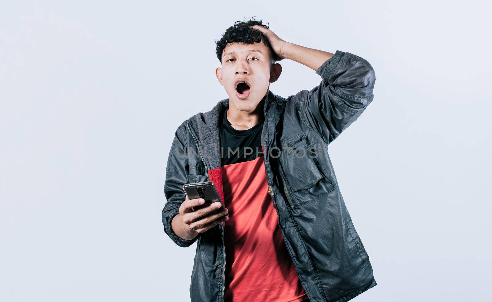 Surprised people with his cell phone holding his head, guy with cell phone shocked looking at camera, amazed man with his cell phone holding his head