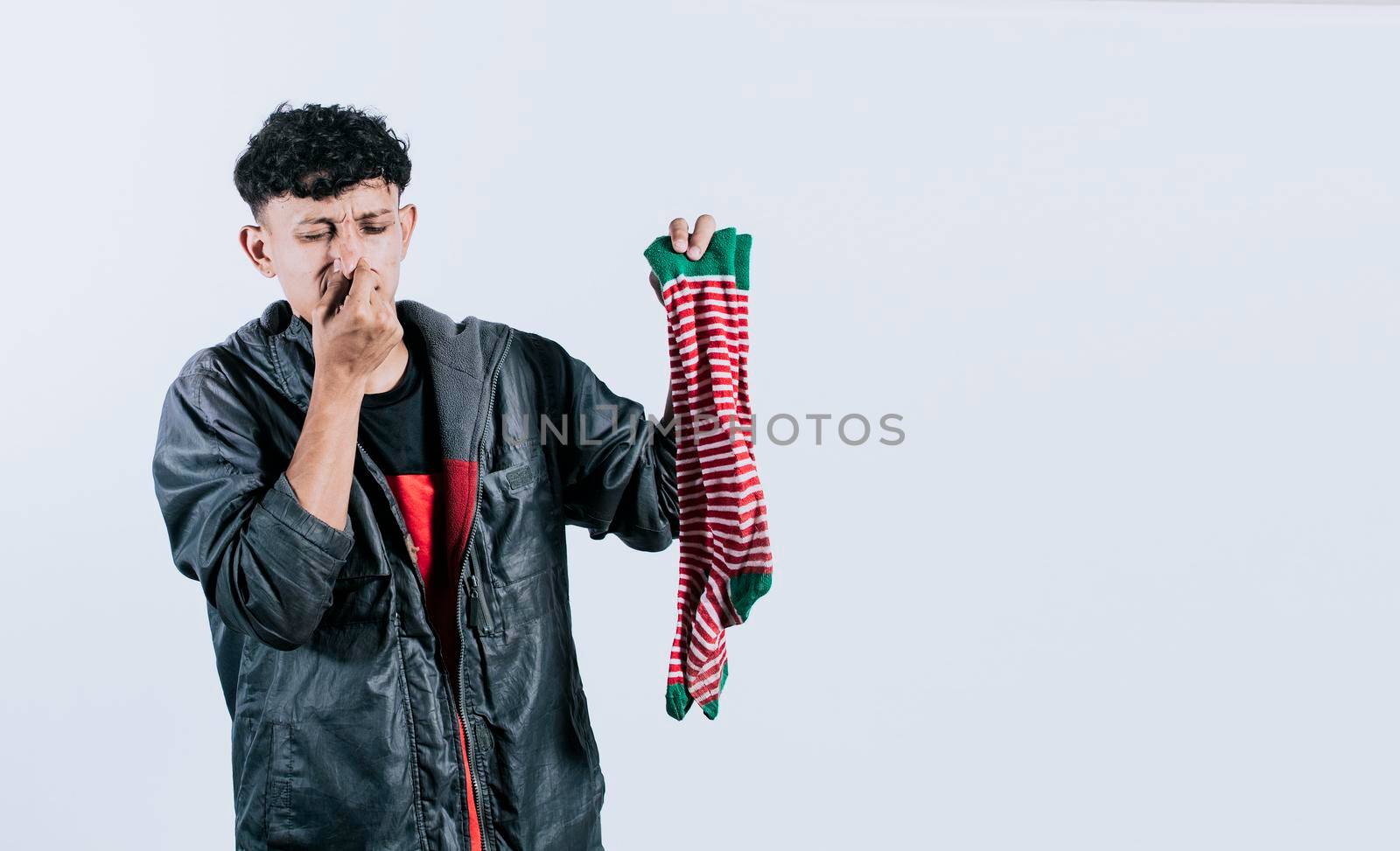 A man with a sock in his hand covering his nose, Person holding a stinky sock in his hand,  smelly socks concept