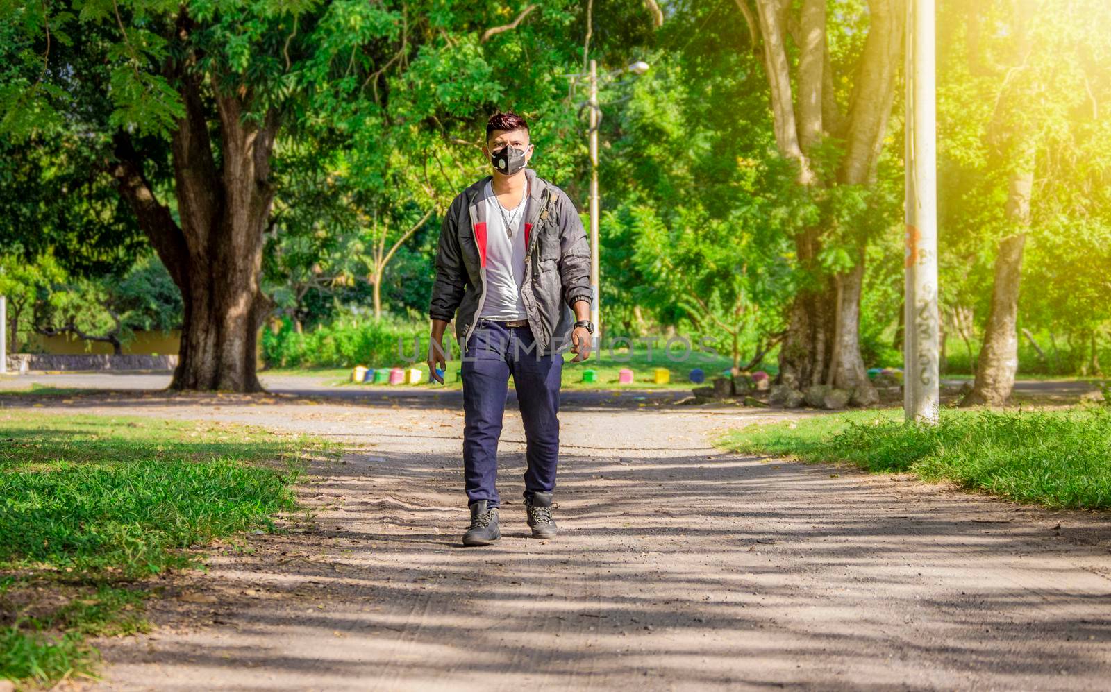 Man walking in the street with face mask on, man walking head-on in the street with face mask, young man with mask walking down the street by isaiphoto