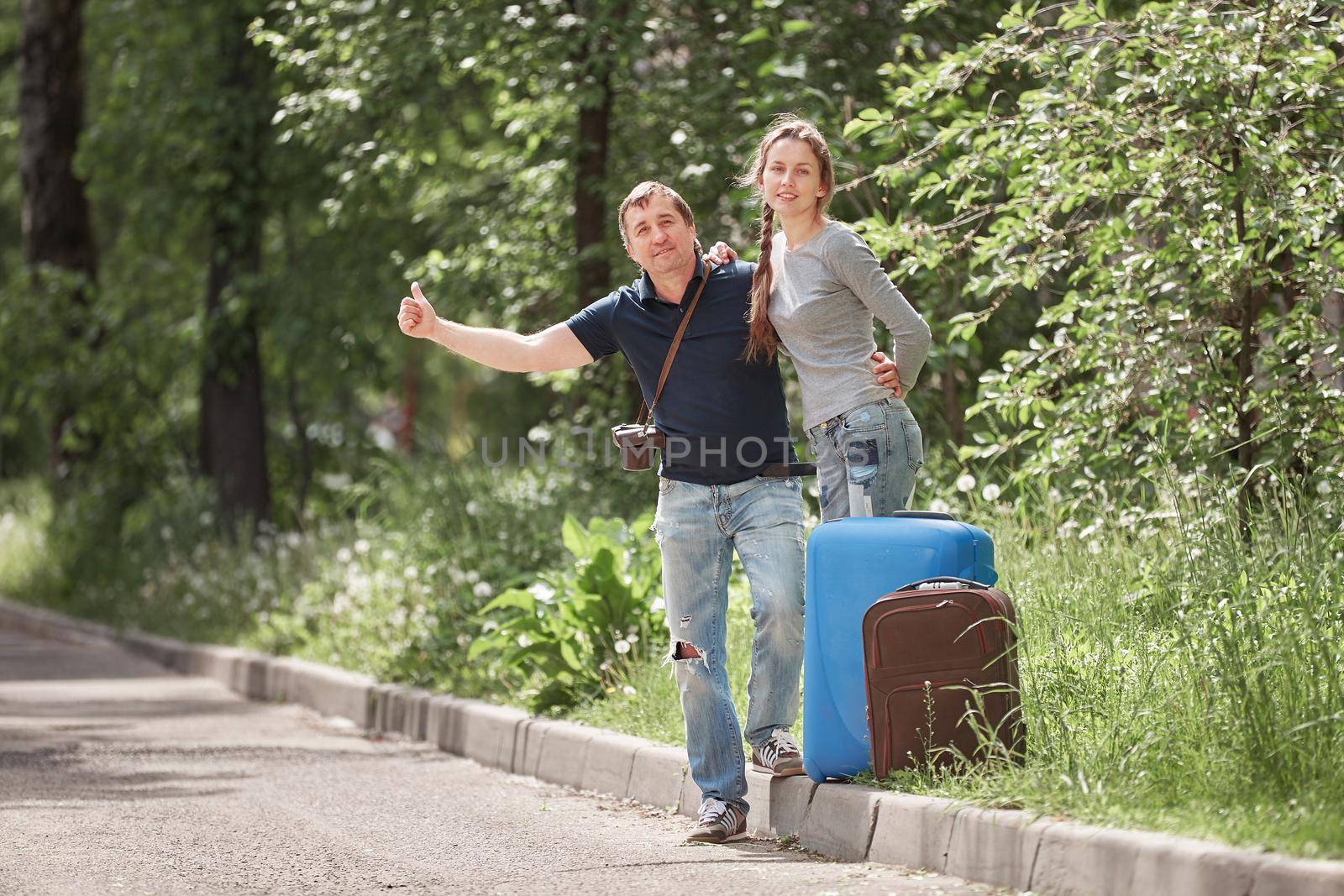 young couple with suitcases voting on the road. the concept of hitchhiking