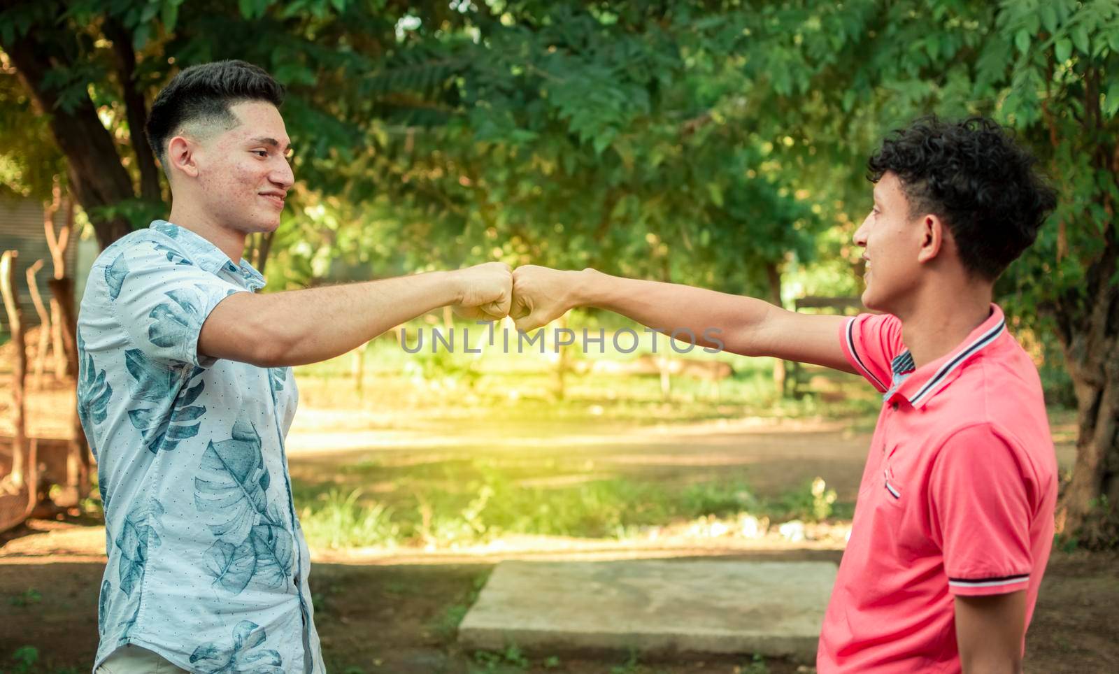 Two young men clashing their fists, image of two young men bumping their fists in a friendly way, close up of two fists bumping in a friendly way