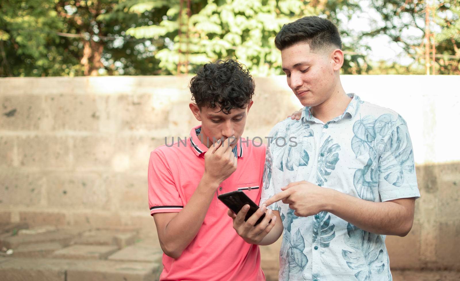 A young man explaining with his cell phone to a young man, A young man showing his cell phone to another young man