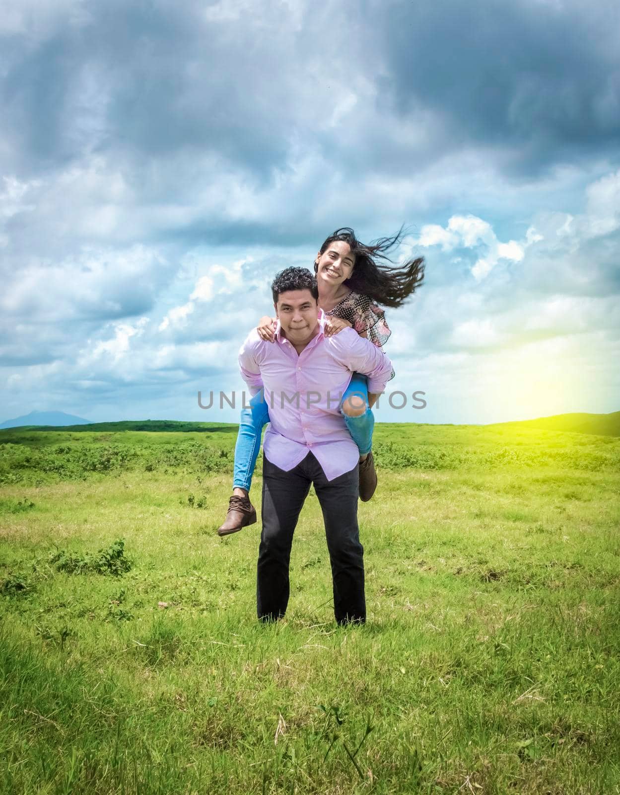 Happy couple in love in the field, happy man carrying his girlfriend in the field by isaiphoto