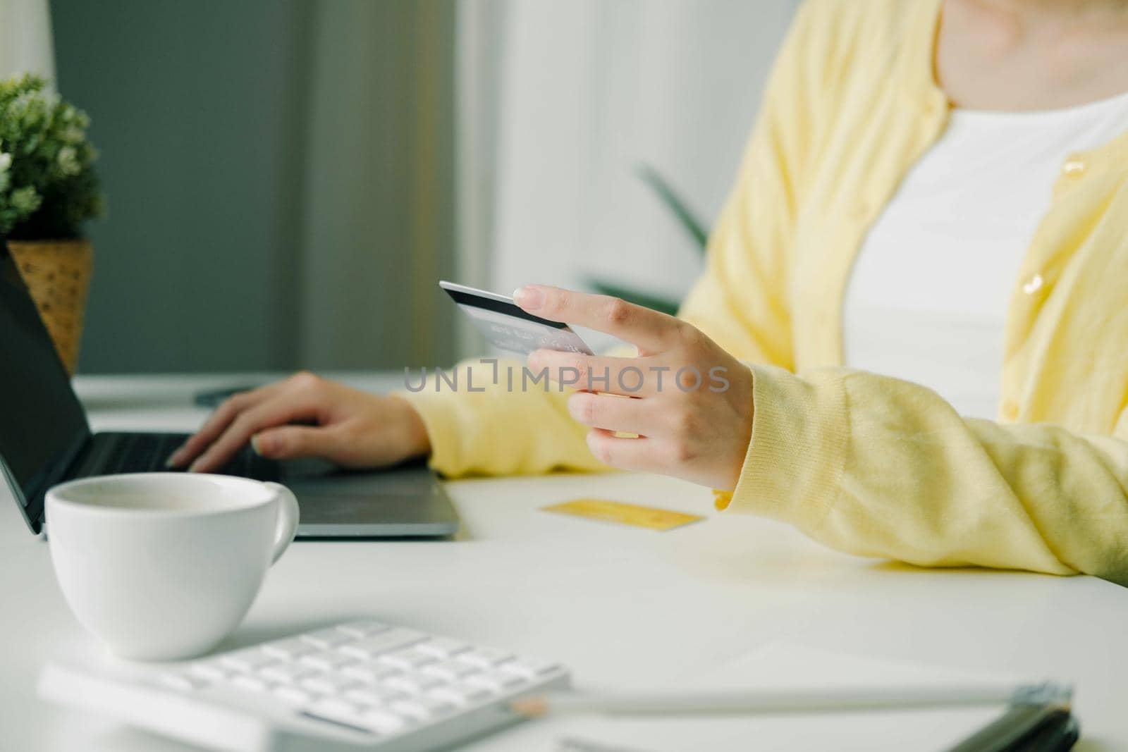 Close up woman using credit card for purchasing and shopping online on laptop computer.