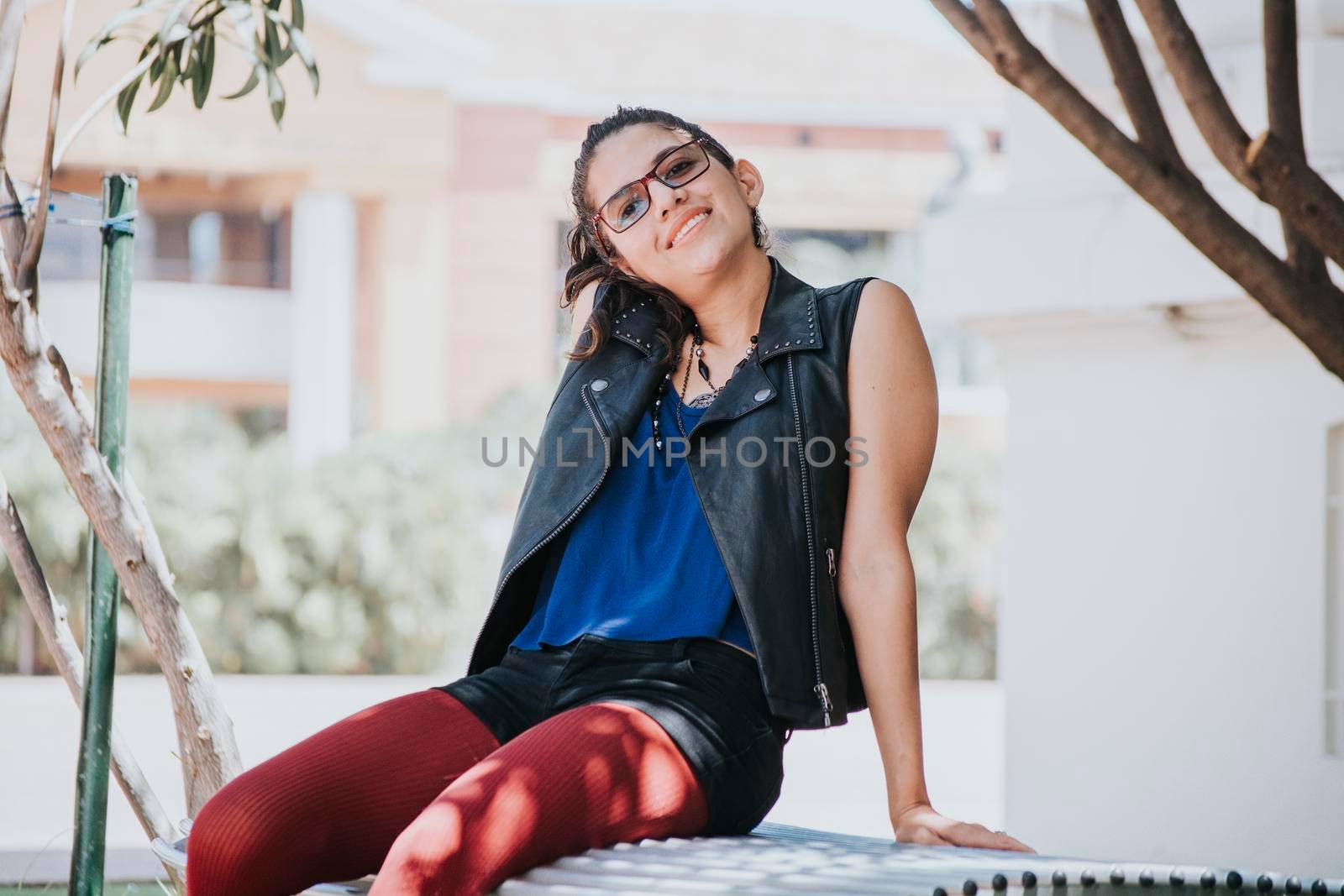 Portrait of an urban girl sitting on a bench, portrait of a latin girl on a bench looking at the camera, concept of a relaxed latin girl looking at the camera