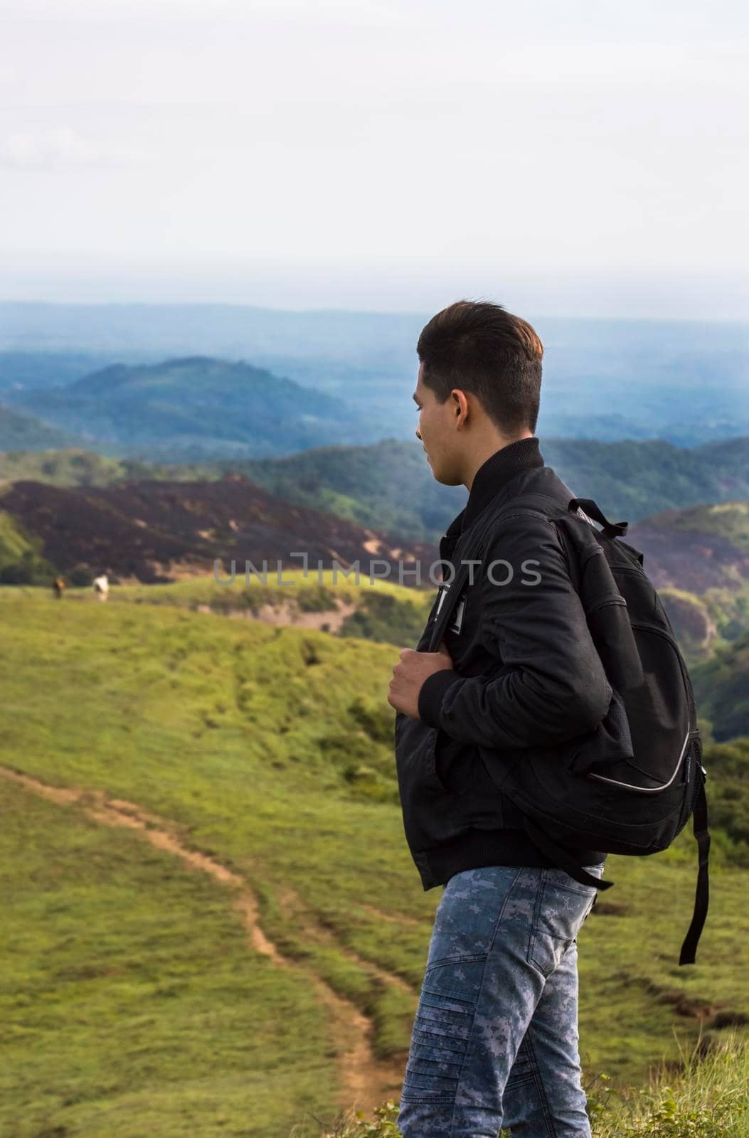 closeup of a backpacker watching a hill, adventurous man watching a hill with background horses on the hill, man with backpack on a hill by isaiphoto