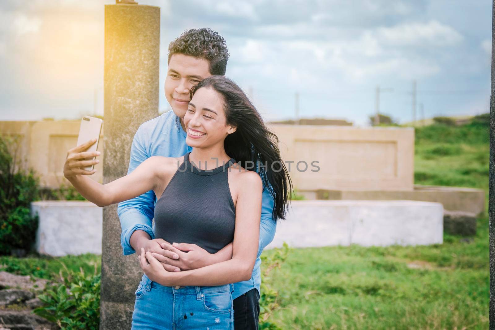 Happy man and woman taking a selfie while hugging from behind, 2 young boyfriends taking a very happy selfie while holding on to the waist by isaiphoto