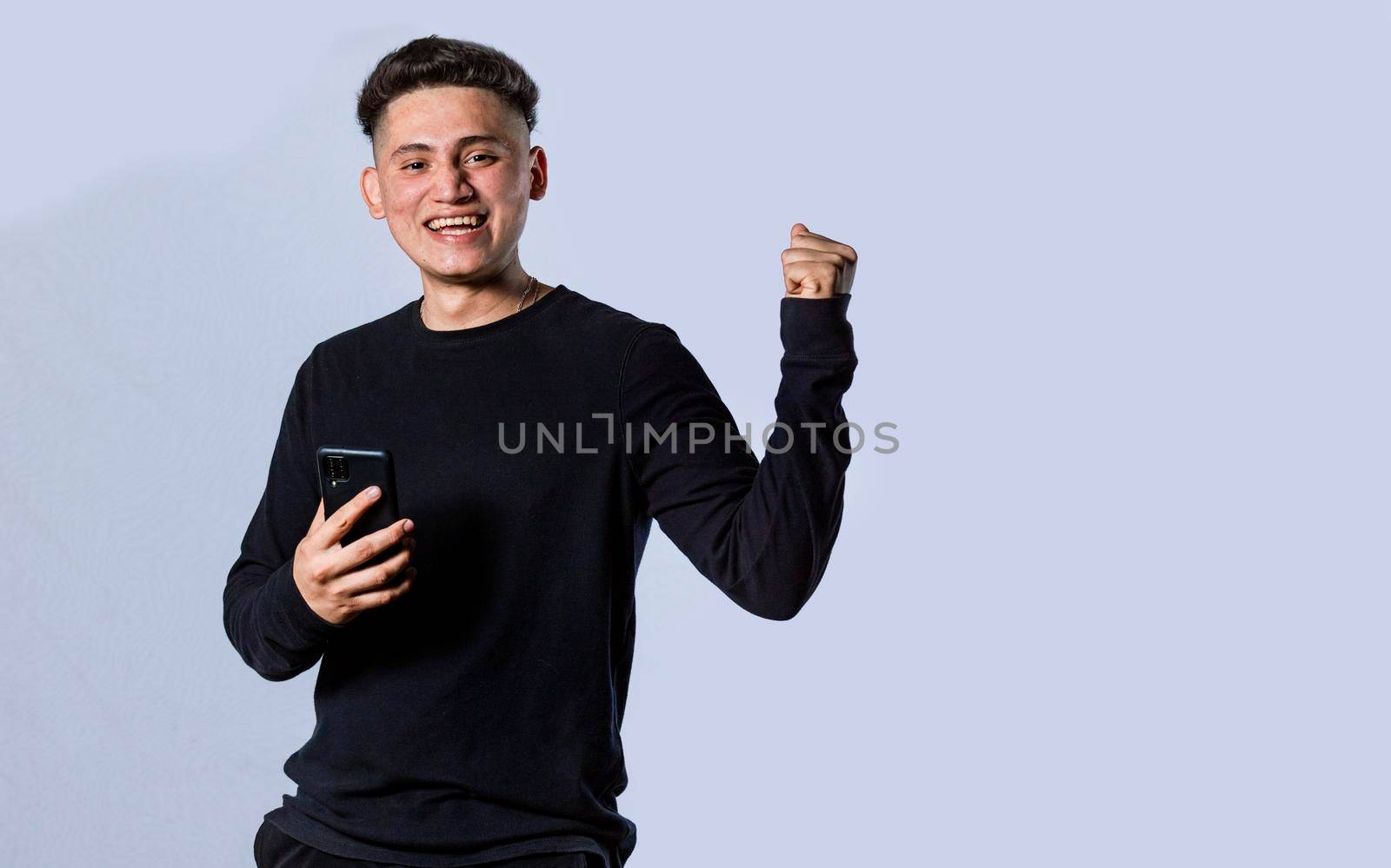 Happy man holding a smartphone and celebrating, Excited guy looking at his smartphone