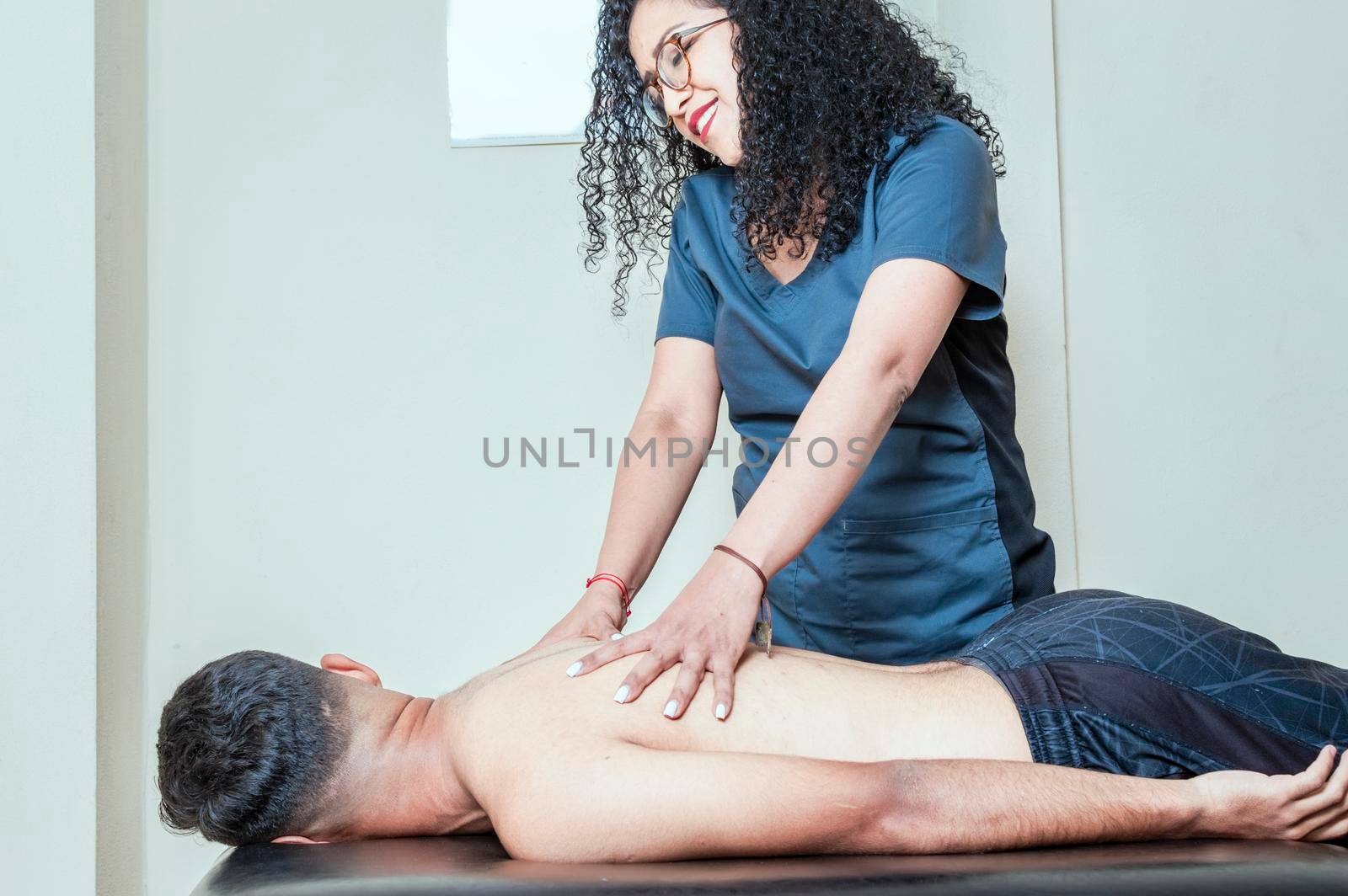 Physiotherapist curing patient's spine problems, man having chiropractic back adjustment. Rehabilitation of sports injuries.