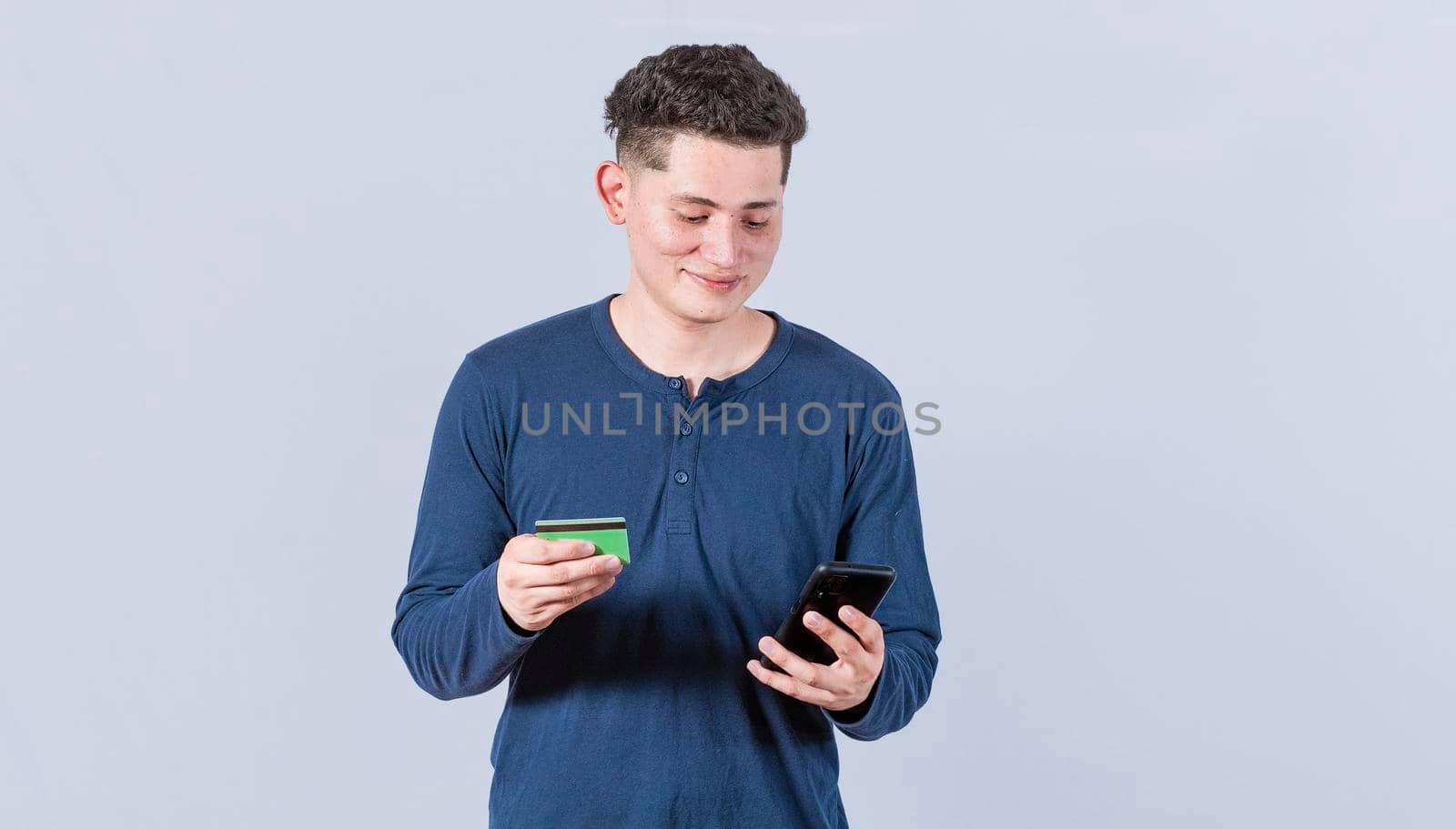 Man holding credit card and cell phone, guy paying from his phone with credit card, electronic payment concept