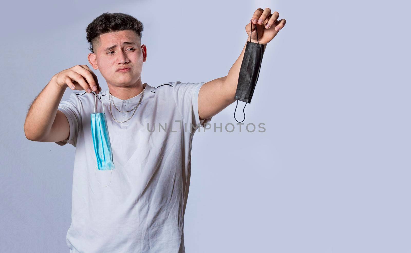 Man deciding to wear surgical mask, Latin man deciding to wear surgical mask on isolated background
