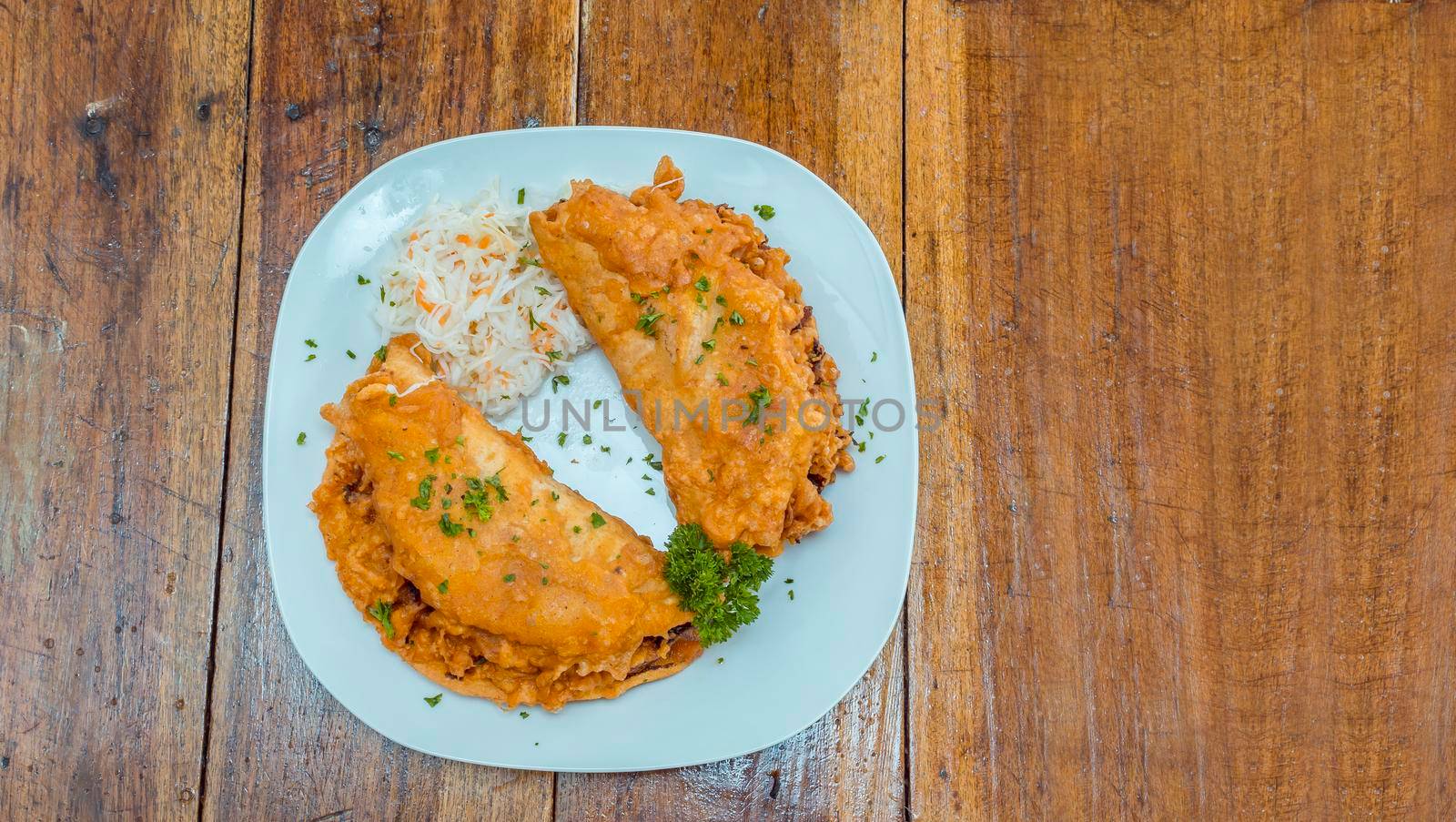 Enchilada served on a plate on wooden table, two enchiladas served on wooden table