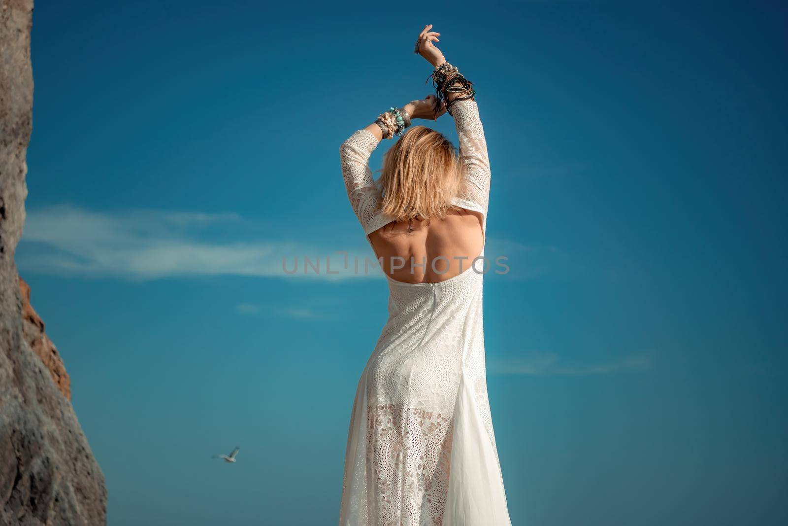 Woman in bohemian clothing on beach at sunset. Boho style for fashionable look on resort. Middle aged well looking woman in white dress and boho style braclets. Summer fashion by panophotograph