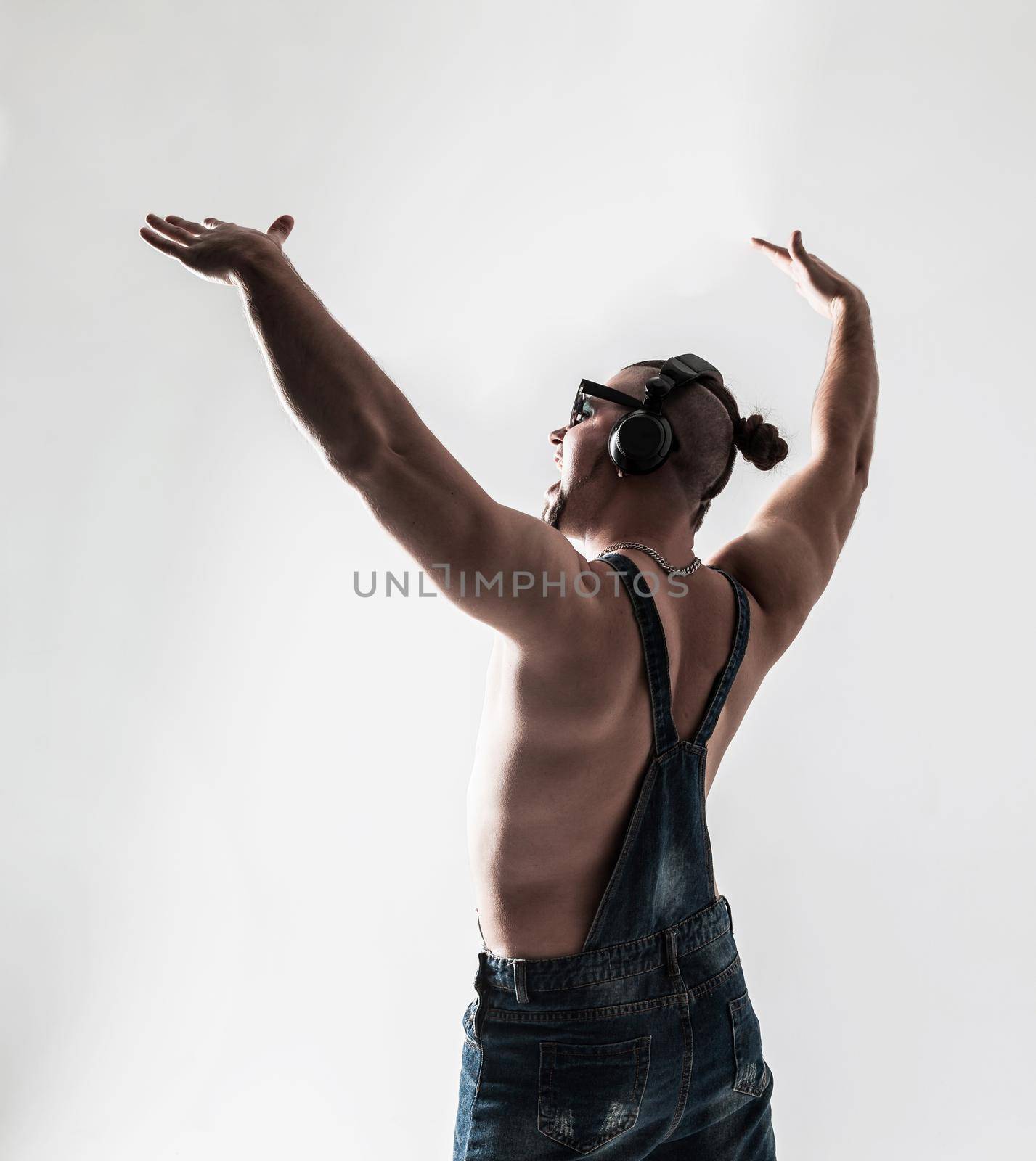 rapper shirtless with headphones and stylish hair and my hands up on a light background . the photo has a empty space for your text