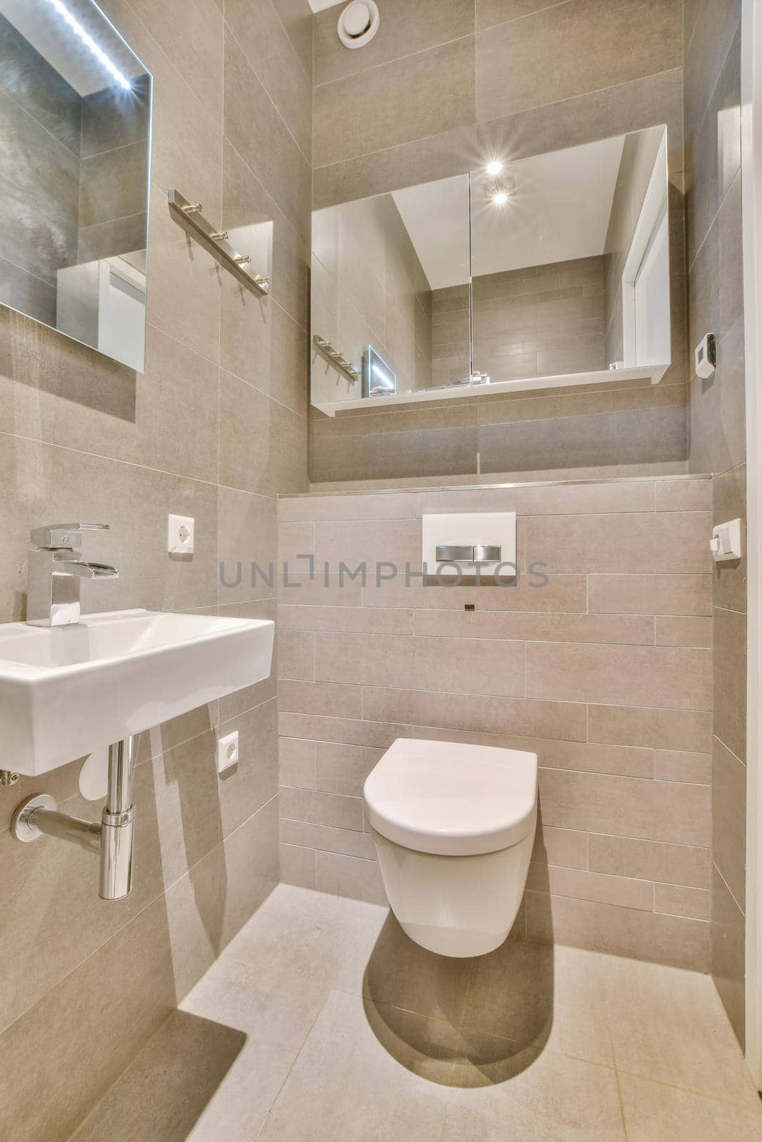 Modern flush toilet and ceramic sink installed on white tiled walls near mirror and towel in small restroom at home