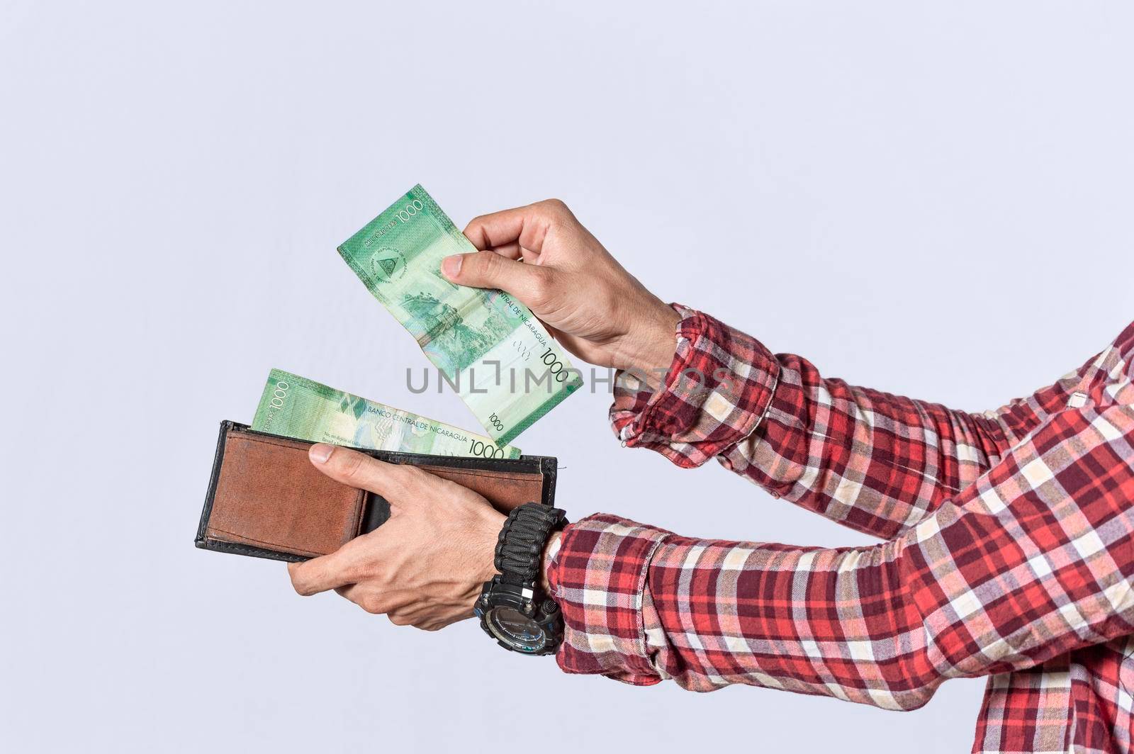 Man taking money out of his wallet, close up of hands taking money out of his wallet isolated, Nicaraguan banknotes, cash payment concept