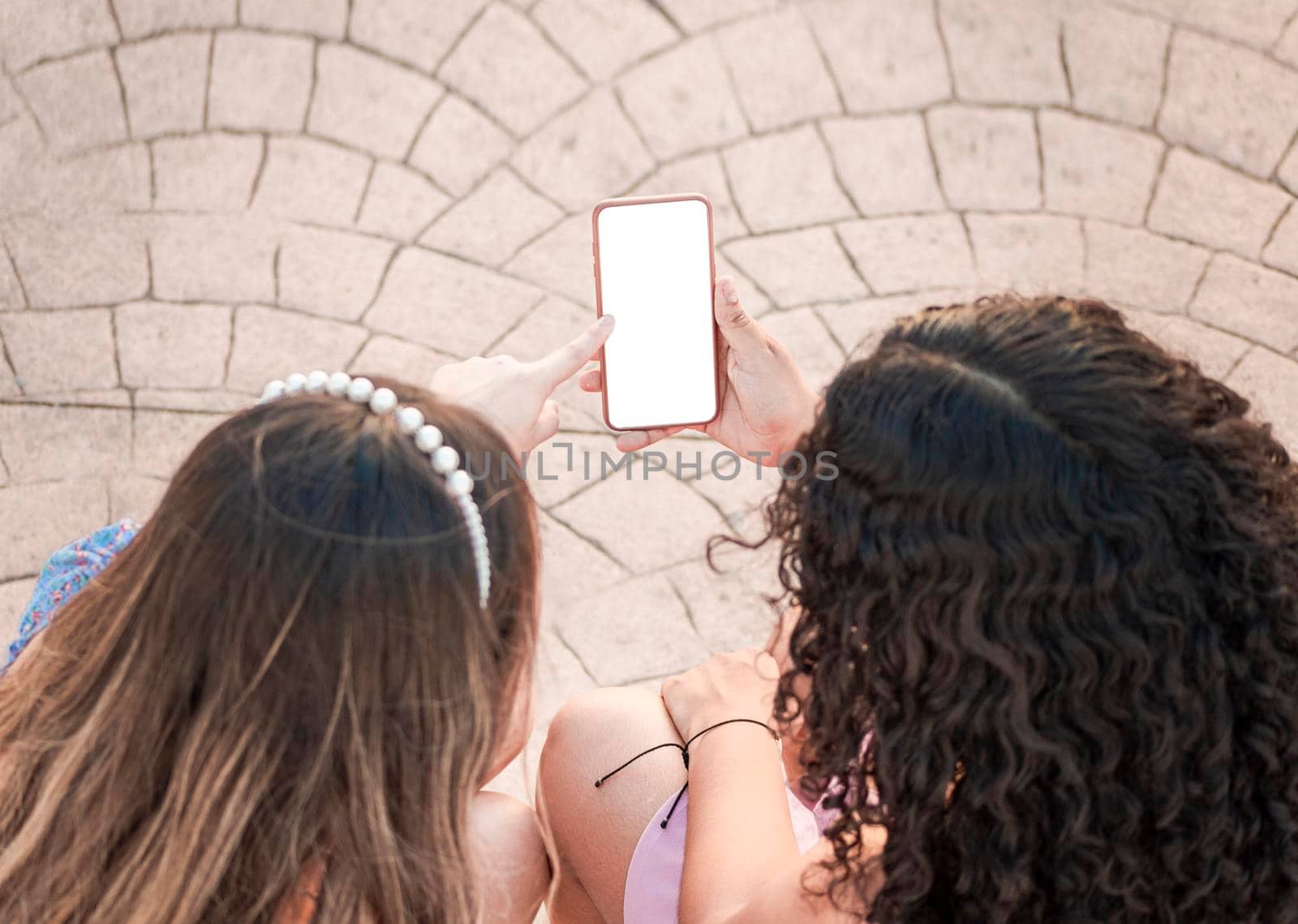 friend showing her cell phone screen, two girls pointing at her cell phone, Girl showing her smartphone to her friend by isaiphoto