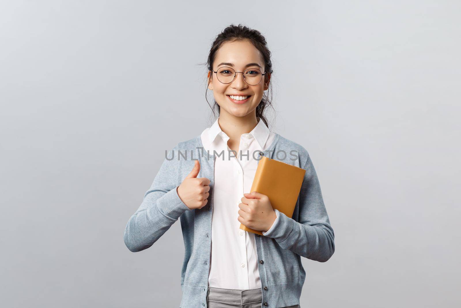 Education, teachers, university and schools concept. Keep up good work. Cheerful young asian woman recommend app, online studying application, show thumb-up and hold planner.