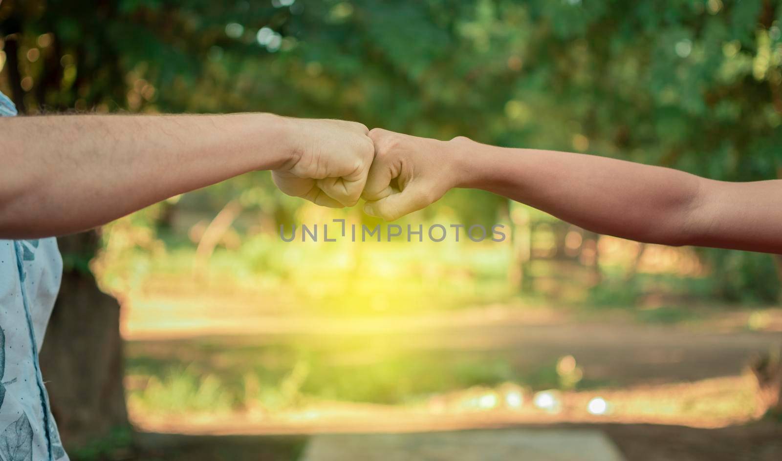 Two young men clashing their fists, image of two young men bumping their fists in a friendly way, close up of two fists bumping in a friendly way