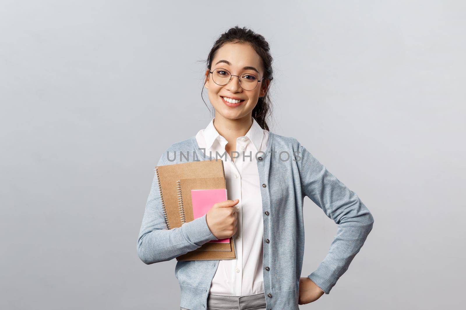 Education, teachers, university and schools concept. Upbeat happy female tutor likes teaching students, standing enthusiastic with prepared study material, hold notebooks smile broadly by Benzoix